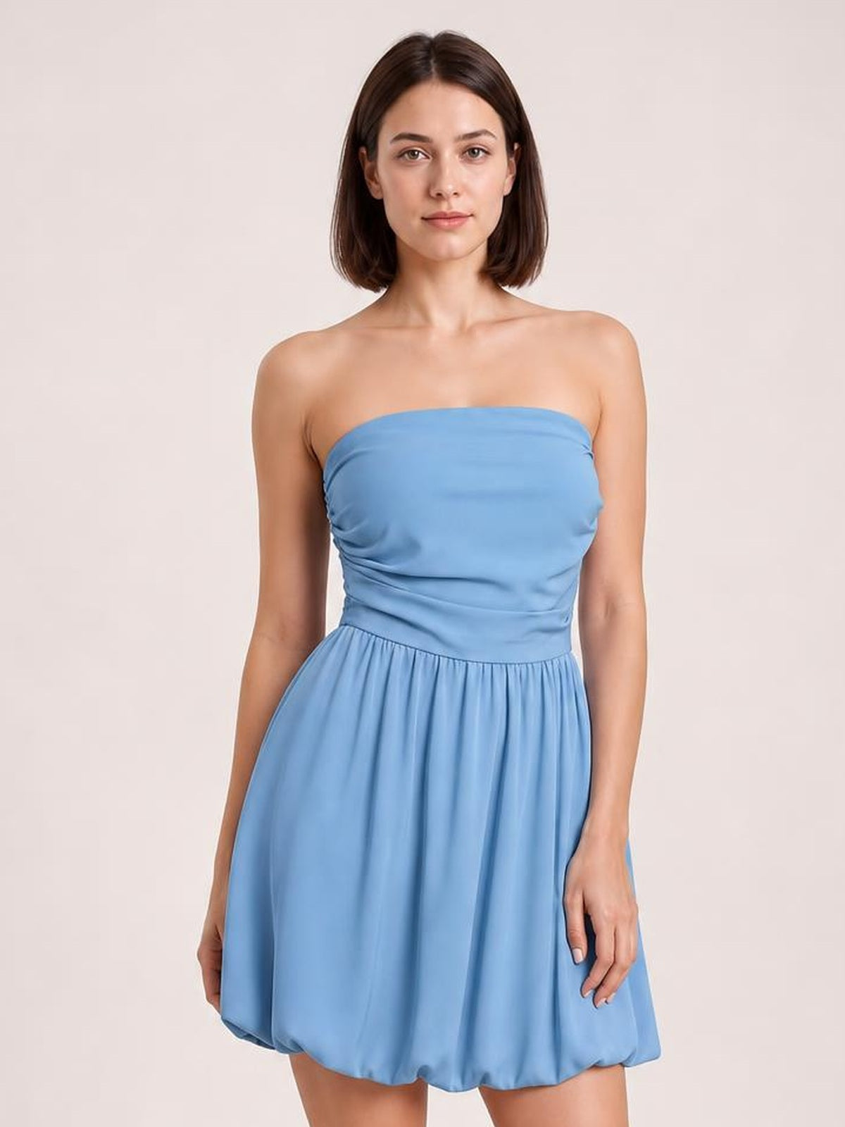 Model wears a light blue ruched tube mini dress with a straight strapless neckline, fitted gathered bodice, and softly flared skirt.