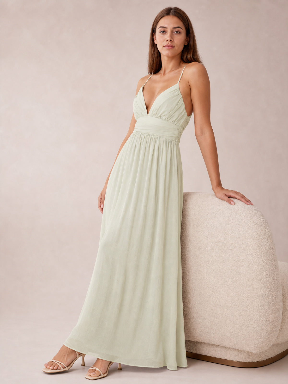 A model poses in a pale sage Ruched V-Neck Cami Dress with slender straps, a gathered bodice, defined waist, and flowing floor-length silhouette.