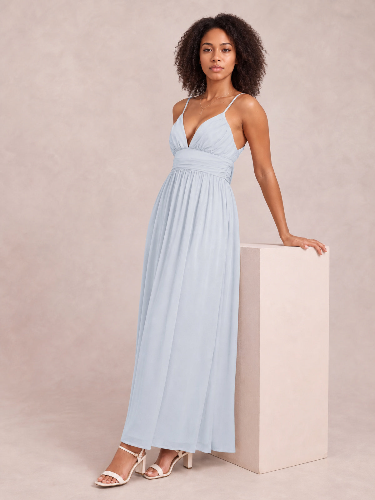 A model poses in a pale blue Ruched V-Neck Cami Dress with slender straps, gathered bodice and waist, and a flowing floor-length silhouette.