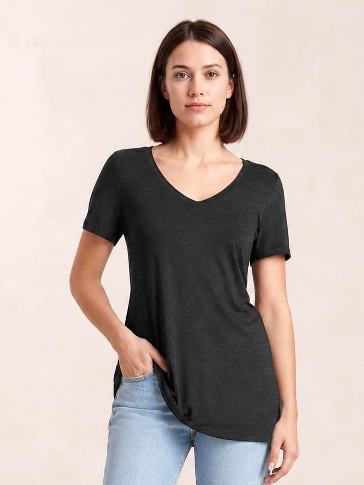 Model wears a black ruched V-neck short sleeve T-shirt with an opaque, relaxed straight silhouette, gently draping over light-wash jeans as one hand rests in a pocket.