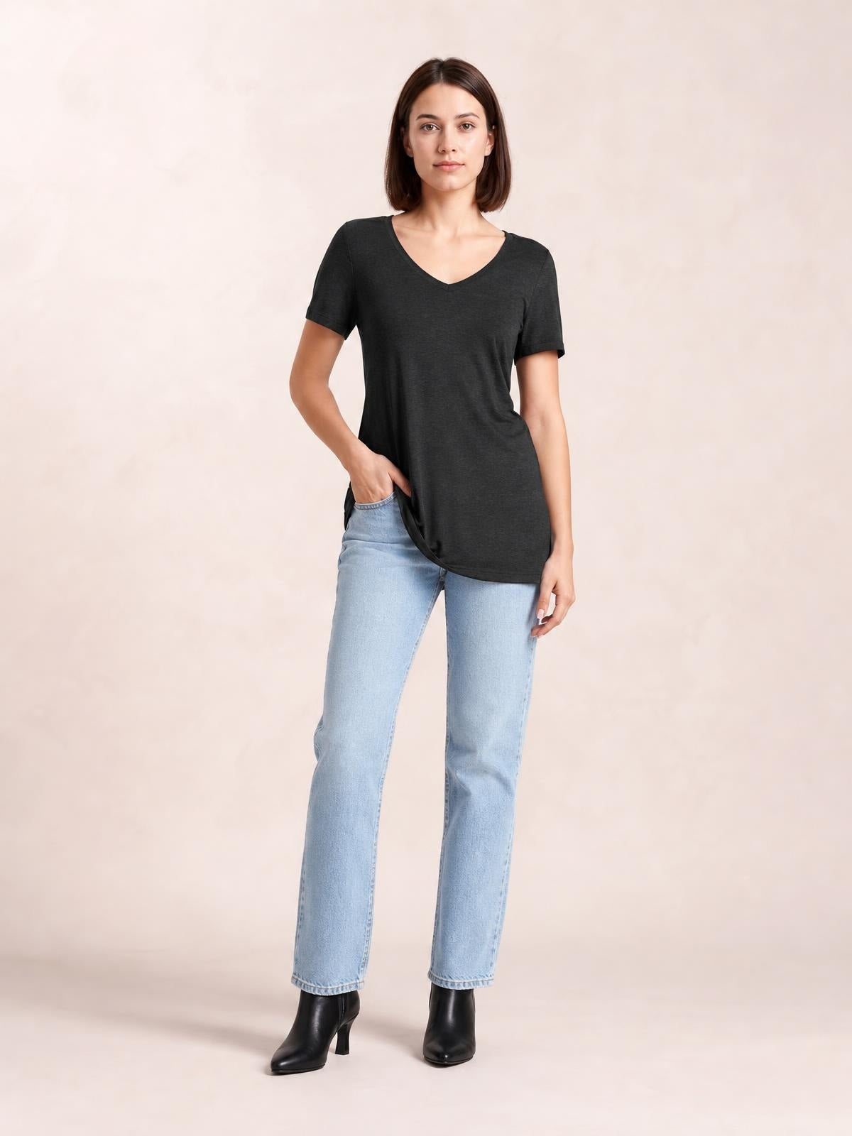 A model poses in a charcoal ruched V-neck short-sleeve T-shirt with a relaxed, slightly elongated silhouette and softly draped construction.