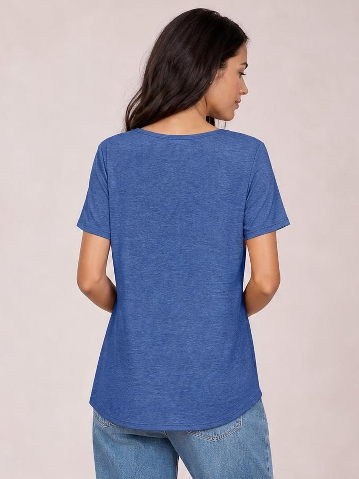 Model shown from the back wearing a blue short-sleeve T-shirt with a relaxed silhouette, smooth construction, and a curved hem extending below the waist.