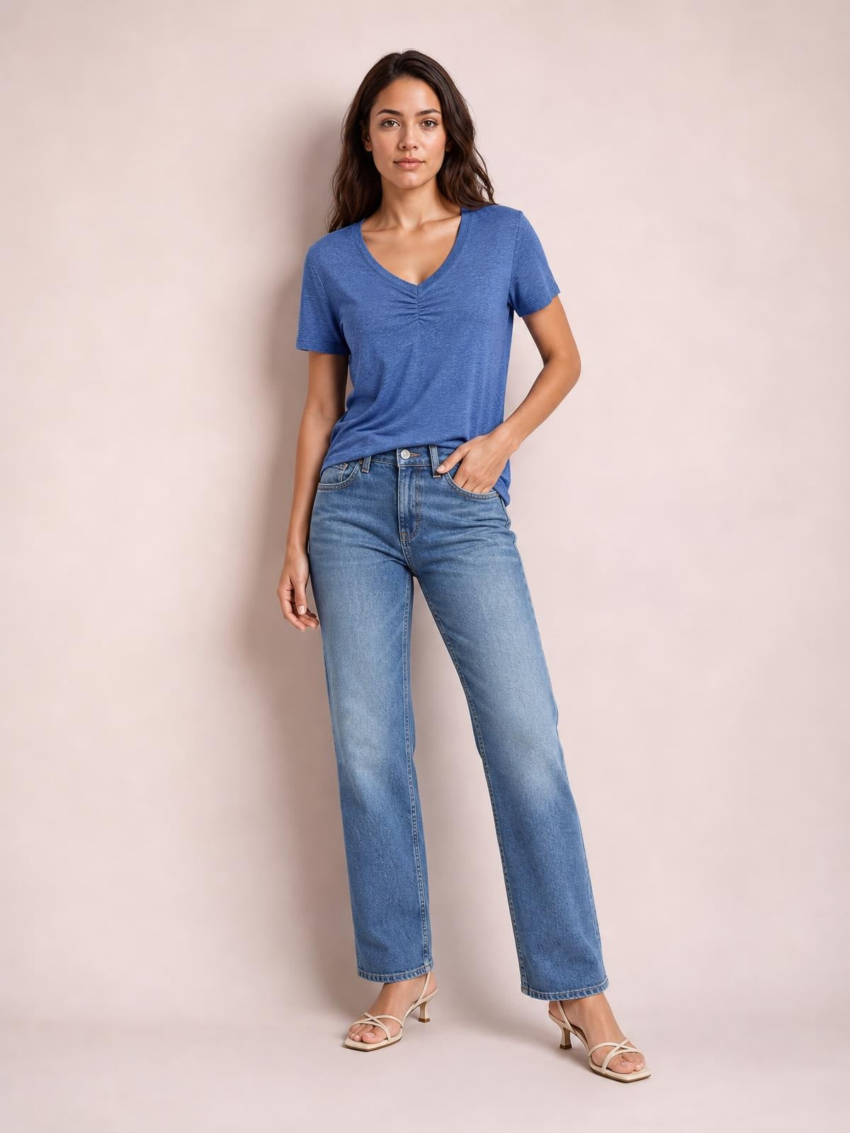 A model poses in a blue ruched V-neck short sleeve T-shirt with center-front gathering and a relaxed silhouette, paired with jeans.