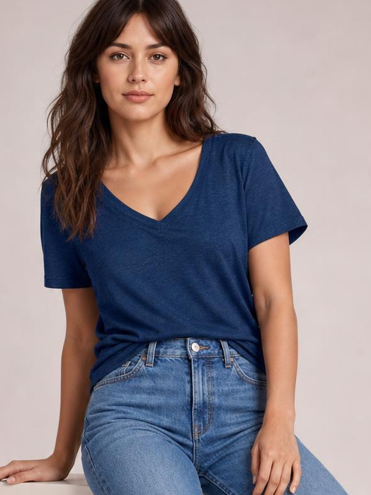 A model poses seated in a navy ruched V-neck short-sleeve T-shirt with a relaxed silhouette and subtle gathered waist detail.