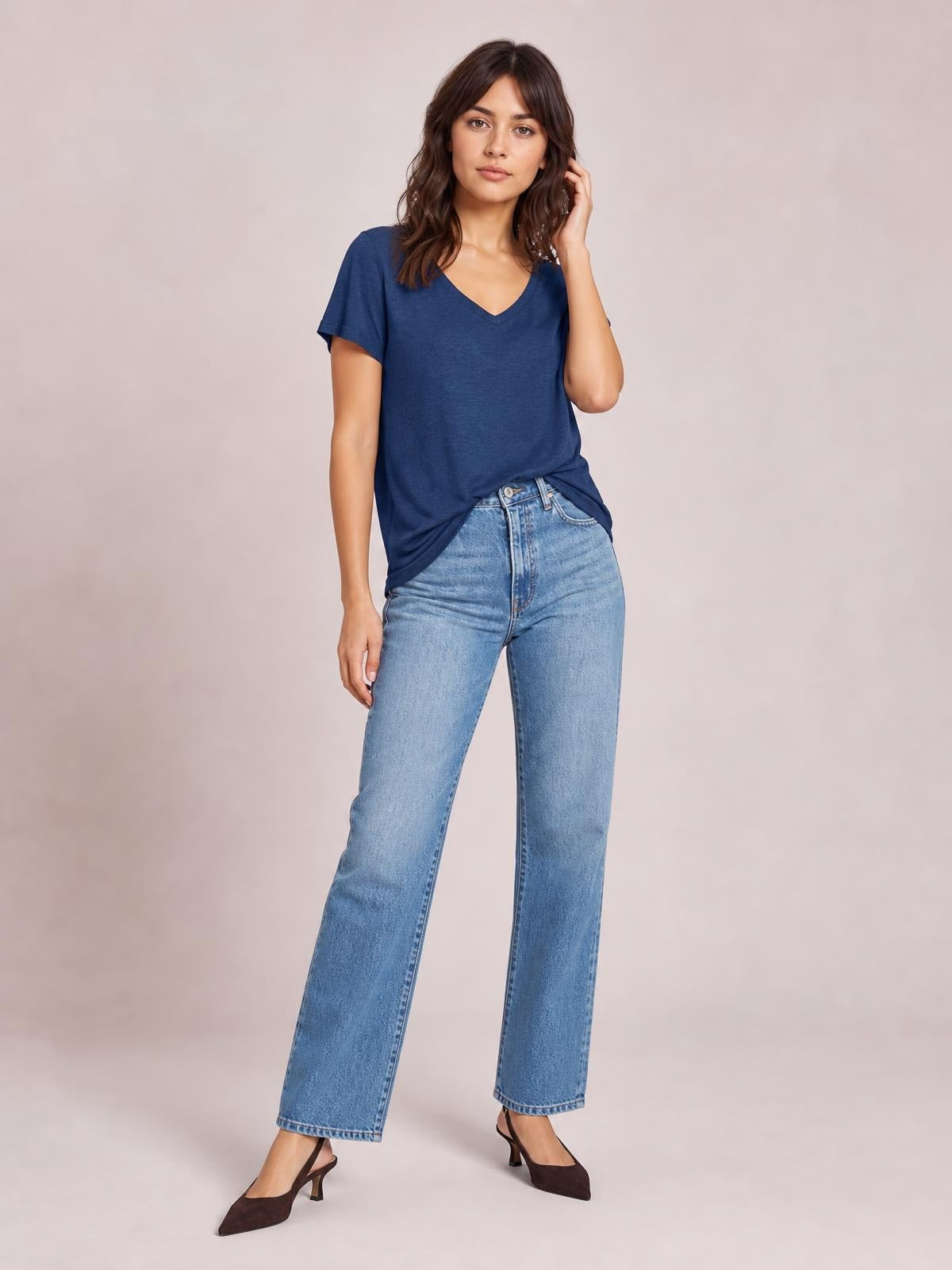 Model poses in a navy blue ruched V-neck short-sleeve T-shirt with a relaxed silhouette and softly gathered hem, styled with light-wash jeans.