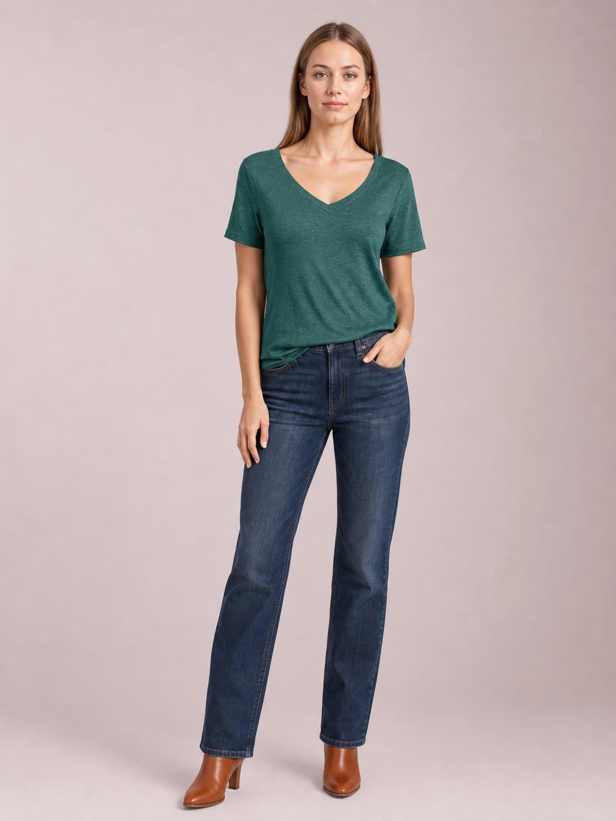 Model wears a dark teal short-sleeve T-shirt with a V-neckline and relaxed straight silhouette, paired with jeans and brown ankle boots.