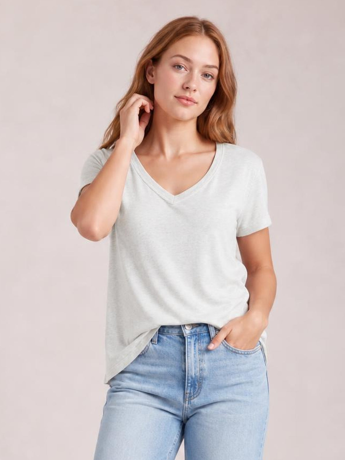 A model wears a light gray Ruched V-Neck Short Sleeve T-Shirt with a relaxed silhouette, softly structured neckline, and slightly loose hem while posing with one hand in her pocket.