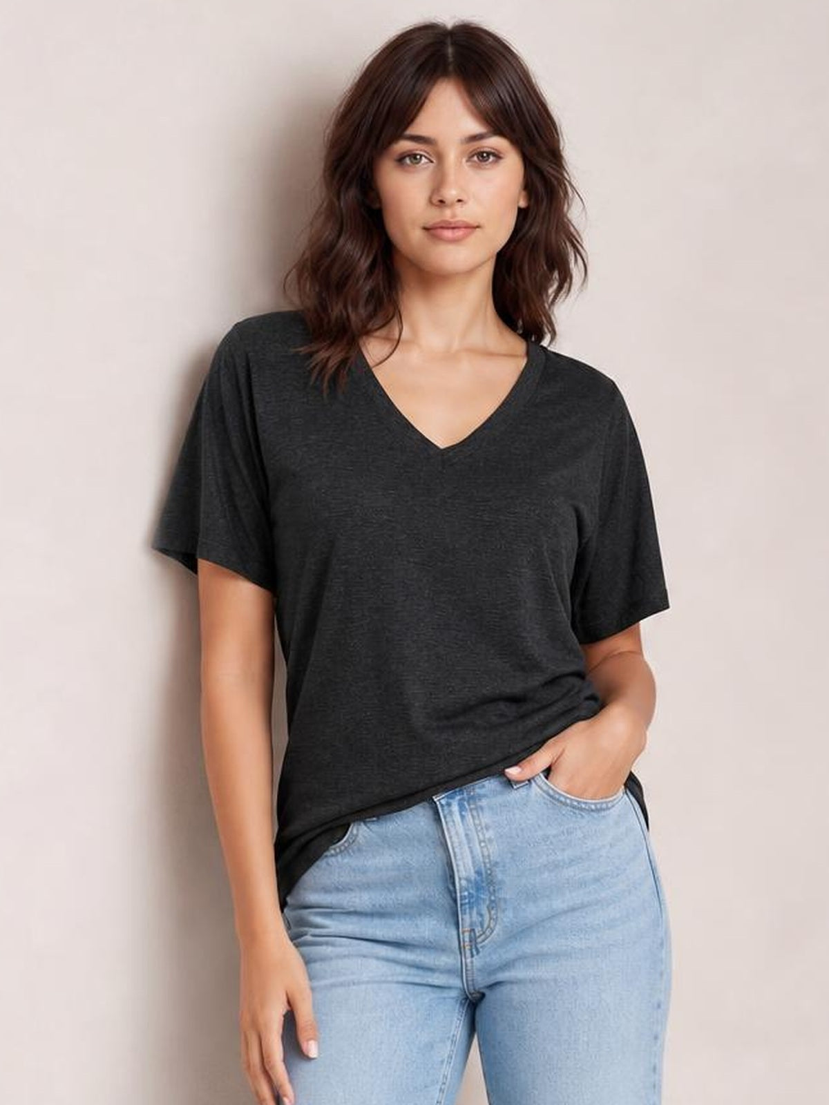Model wears a charcoal ruched V-neck short sleeve T-shirt with a relaxed silhouette, paired with light-wash jeans and one hand in a pocket.