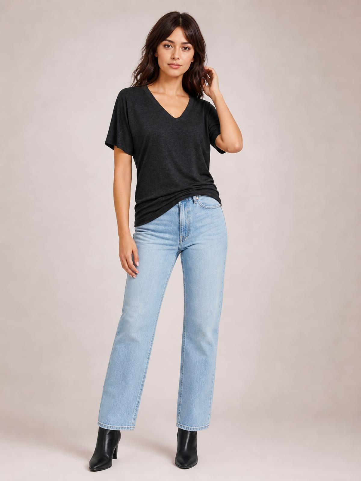 Model poses in a dark charcoal ruched V-neck short sleeve T-shirt with a relaxed silhouette, paired with light-wash straight-leg jeans.