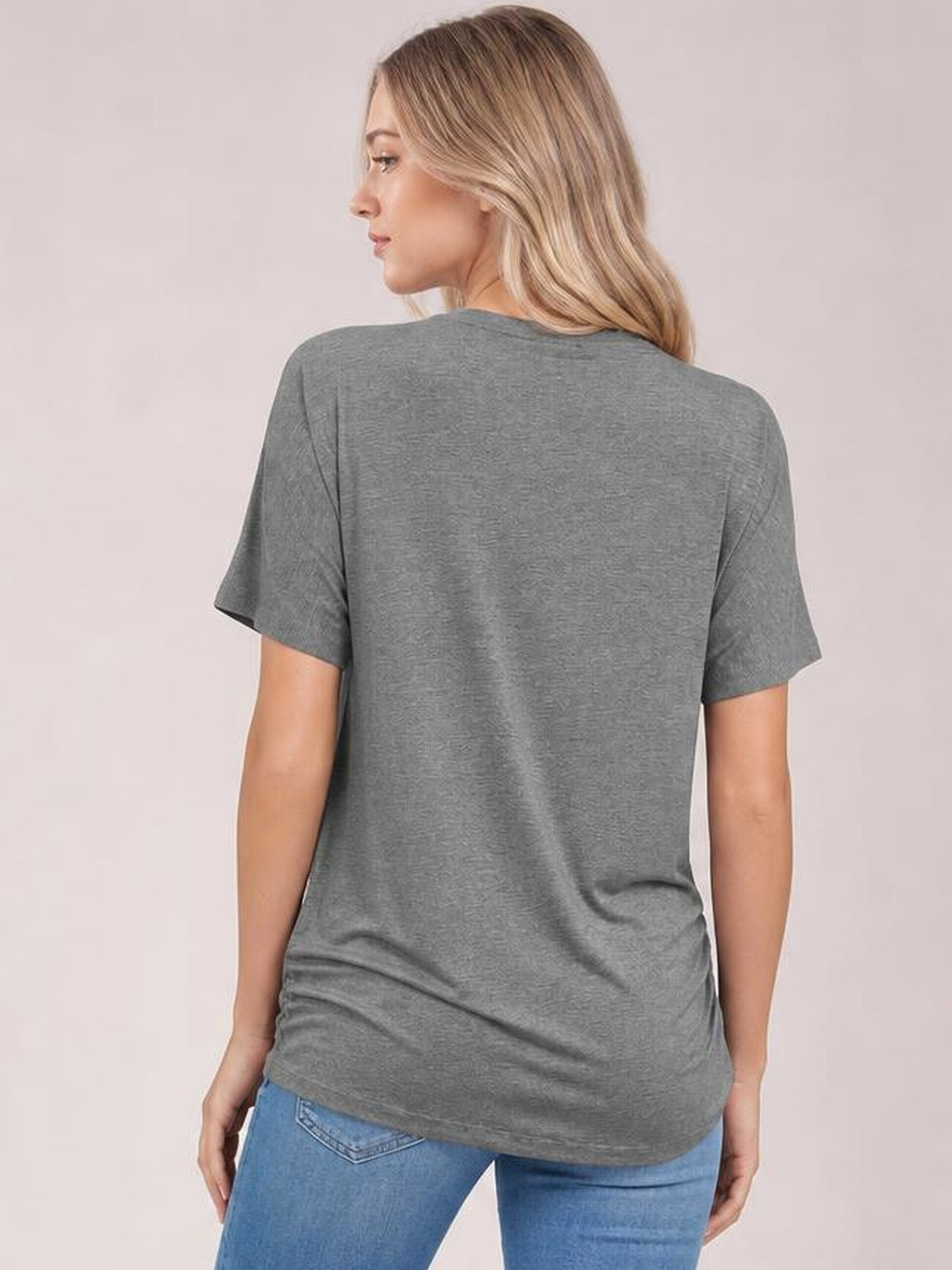 A model stands turned away in a gray short sleeve T-shirt with a relaxed silhouette, soft drape, and gently curved hem.