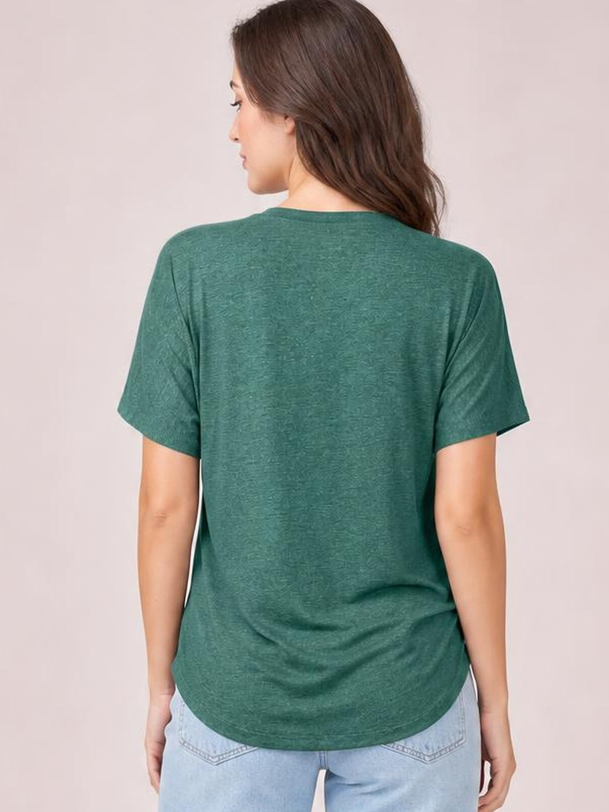 A model stands facing away in a green short-sleeve T-shirt with a relaxed silhouette, smooth construction, and rounded hem.