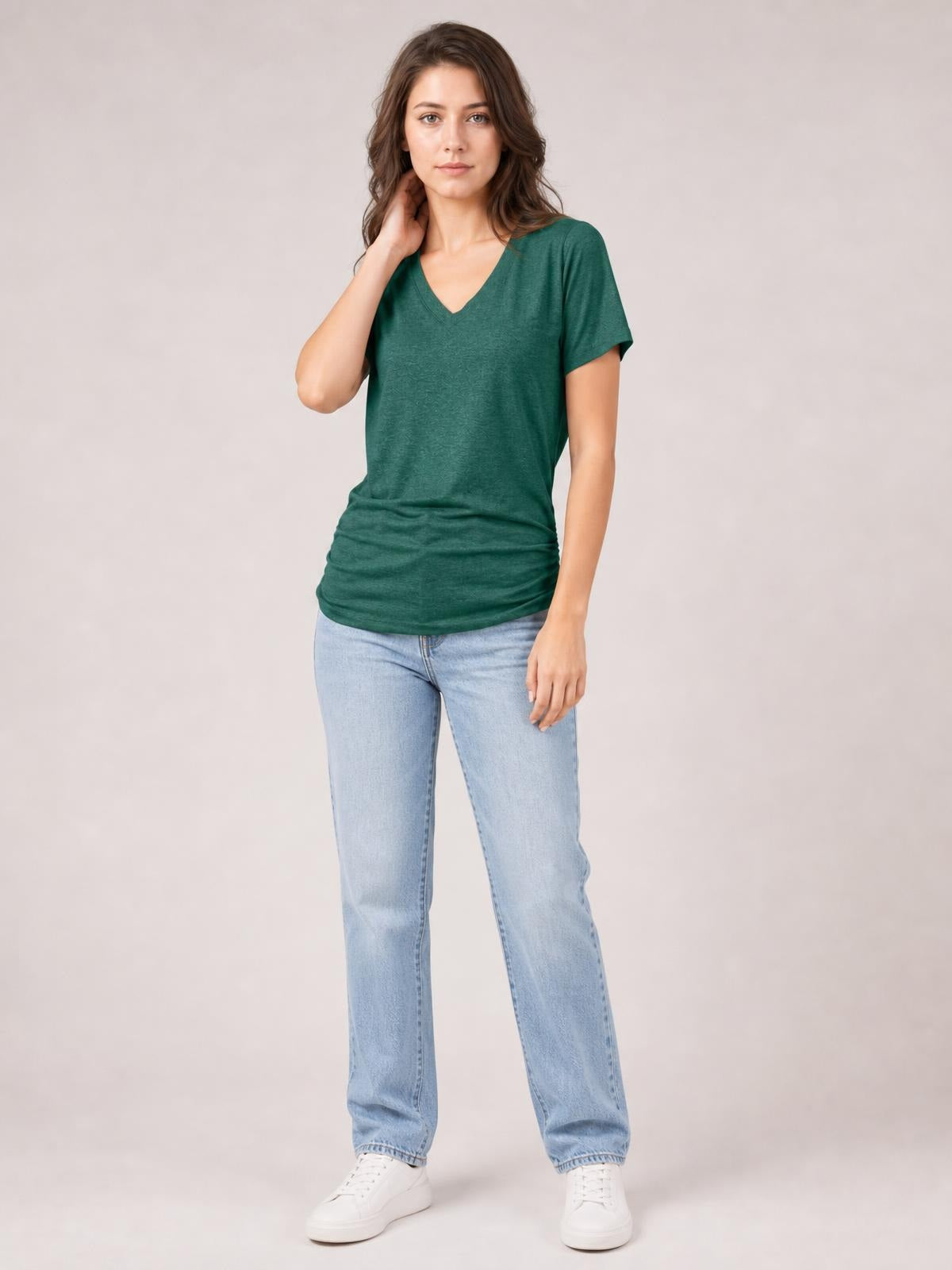 Model in a relaxed pose wearing a forest green ruched V-neck short sleeve T-shirt with a soft, stretchy fit and gathered waist.