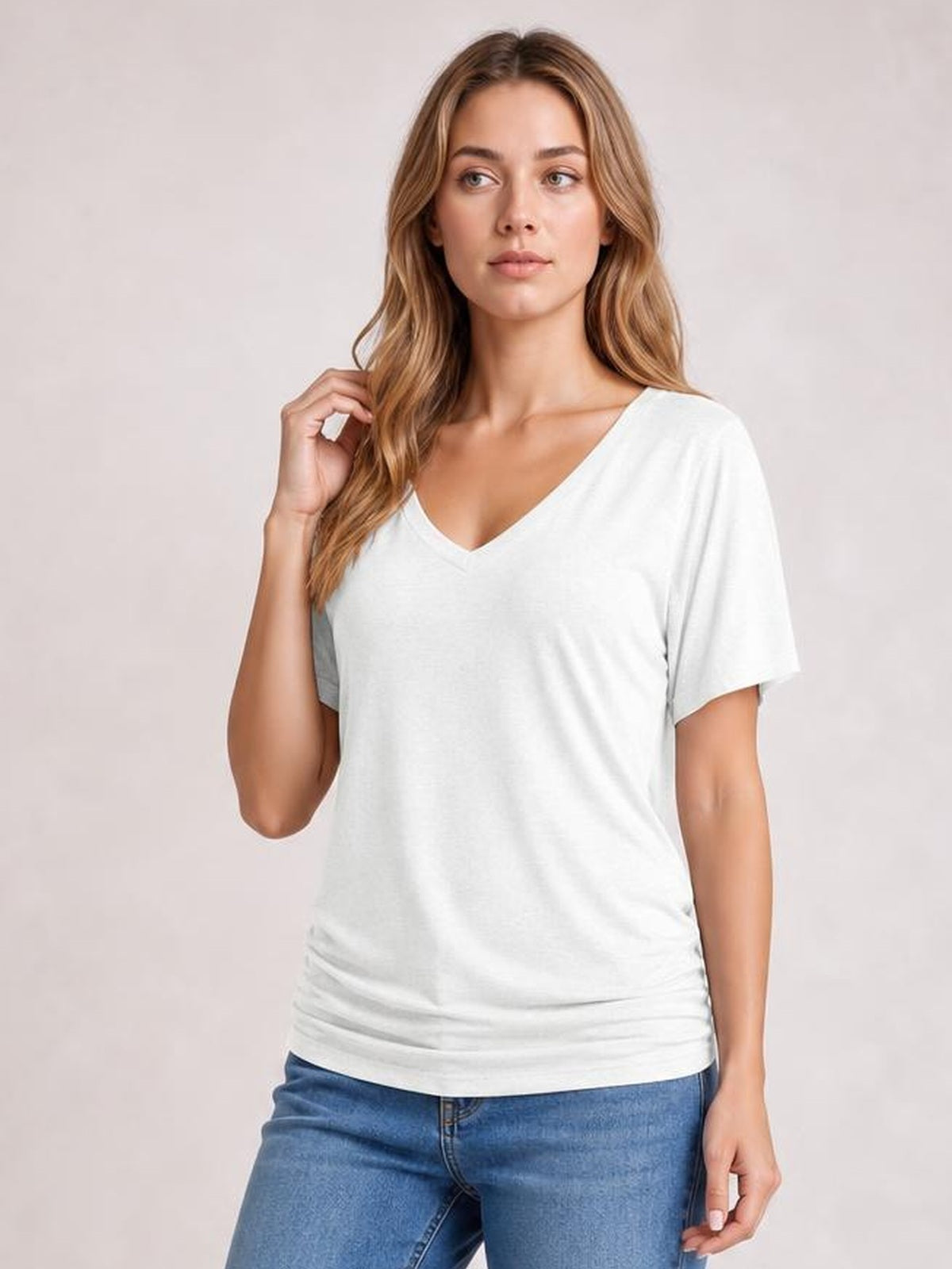 Model wears a white ruched V-neck short sleeve T-shirt with a relaxed silhouette, gathered hem, and soft stretchy construction.