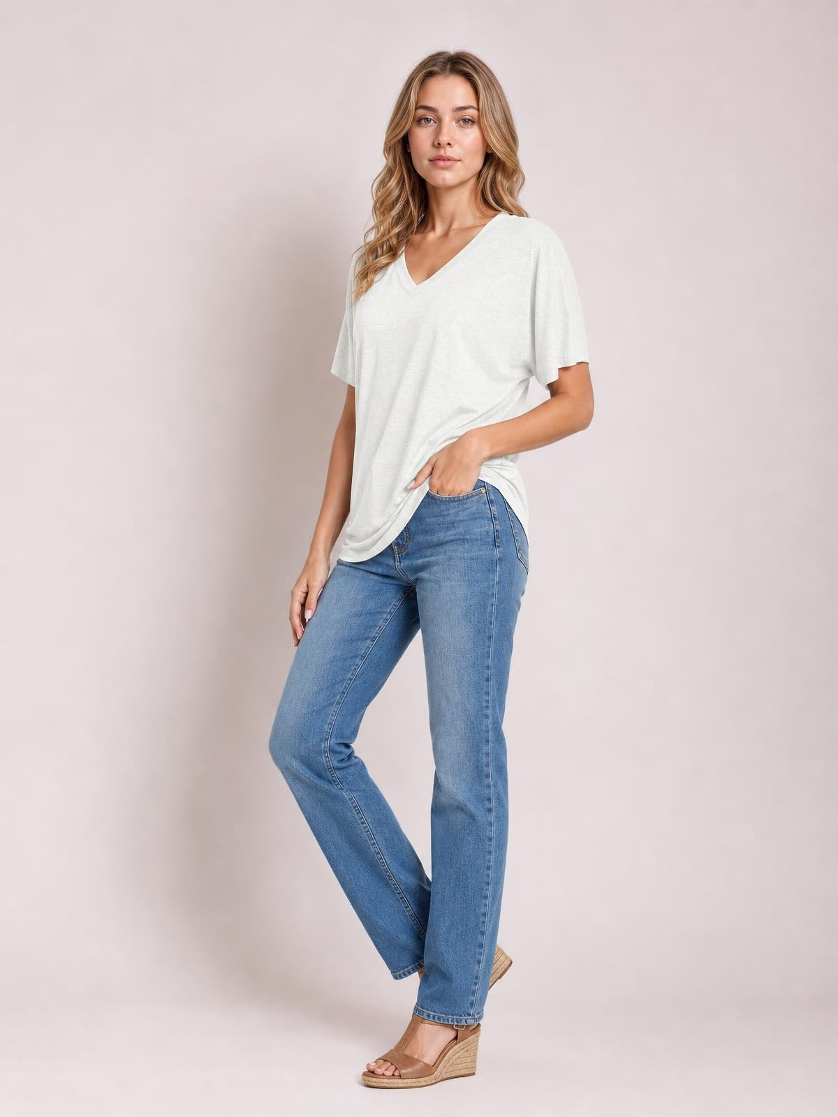 A model poses in a white ruched V-neck short-sleeve T-shirt with a relaxed silhouette, gently gathering the hem at one side.