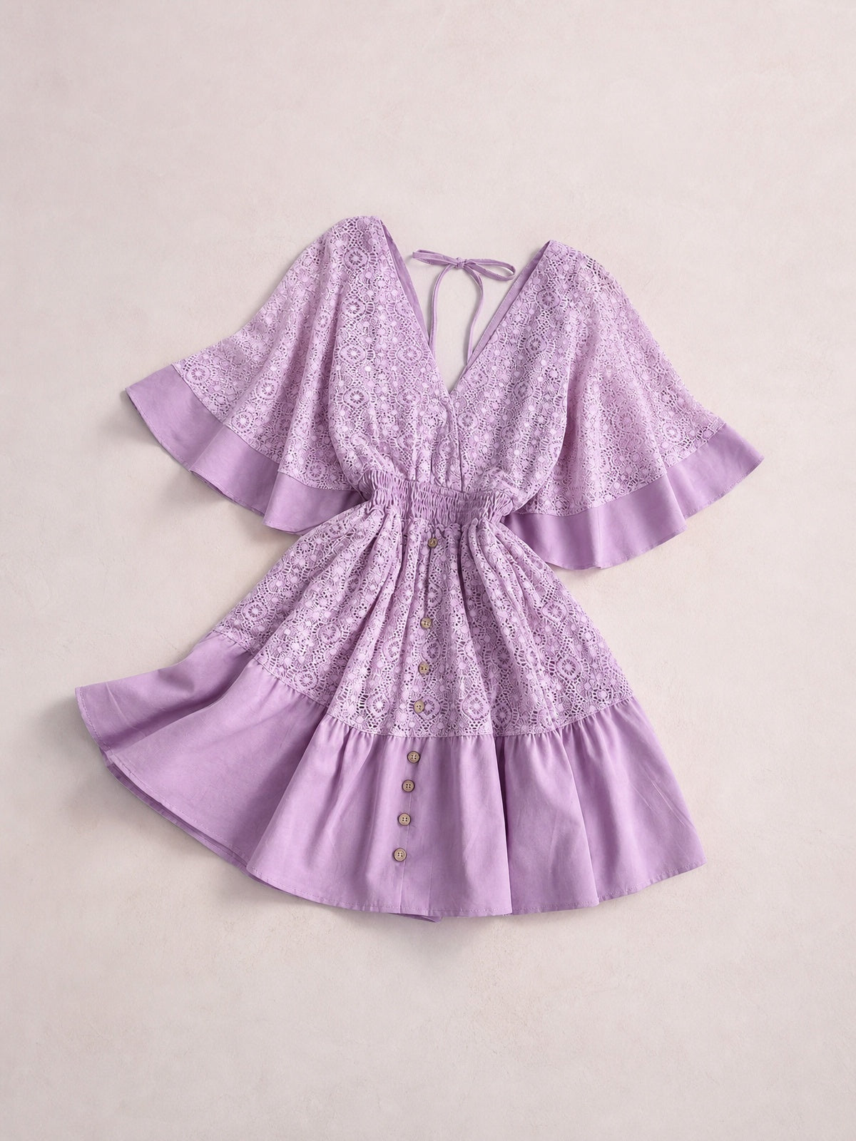 Lavender lace mini dress with a V-neck, tie-back opening, smocked waist, flared silhouette, bell sleeves, ruffled hems, and button-front skirt.