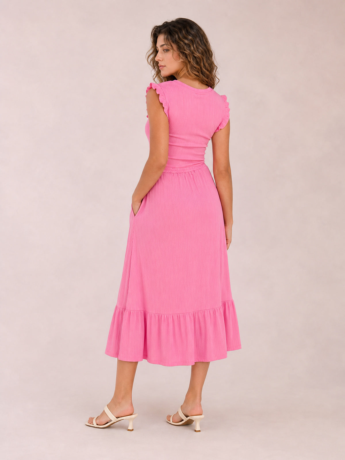 Model poses in a bright pink ruffle-trim round-neck top and drawstring midi skirt set, featuring a fitted silhouette, side pockets, and tiered hem.
