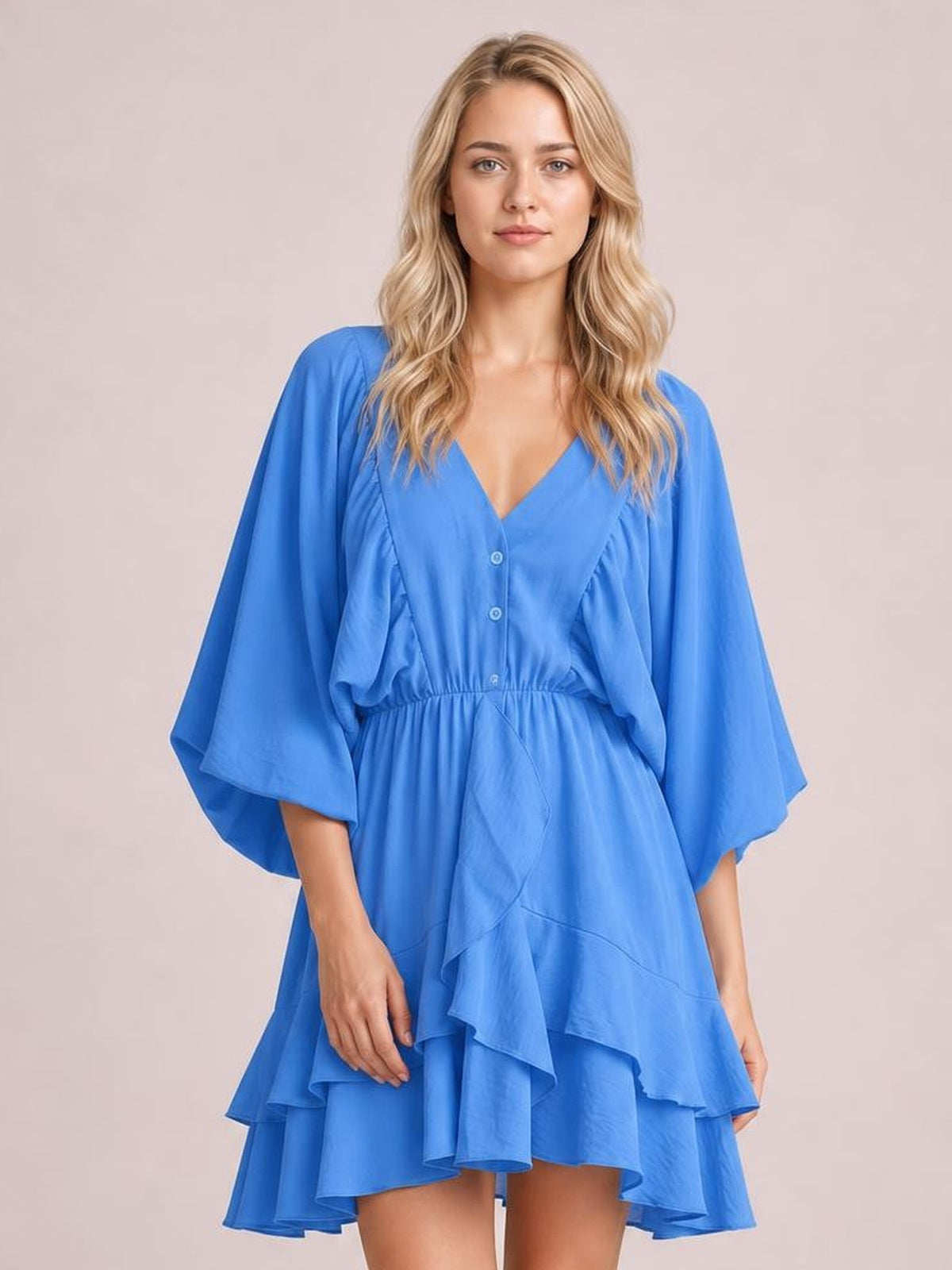 A model stands in a bright blue mini dress with a V-neck, button-front bodice, elastic waist, tiered ruffled skirt, and voluminous balloon sleeves.