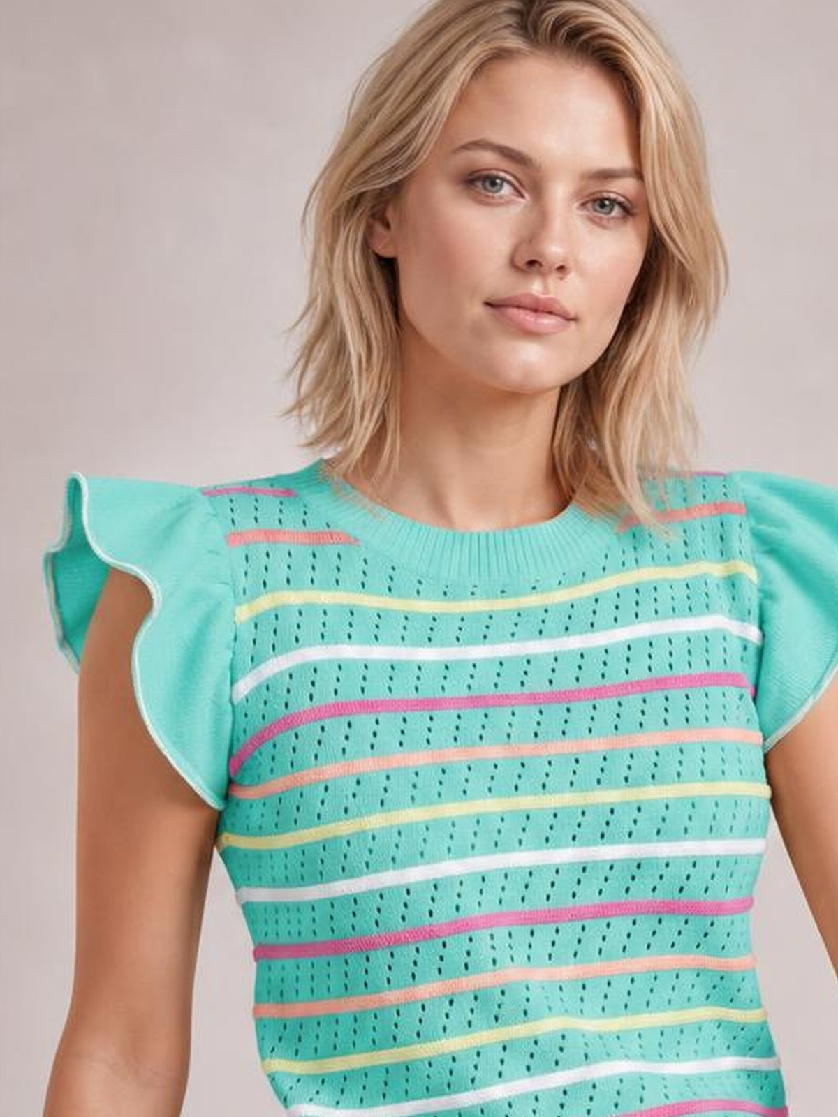 Model wears a turquoise striped knit top with a round neck, eyelet texture, ruffled cap sleeves, and a fitted silhouette while facing the camera.