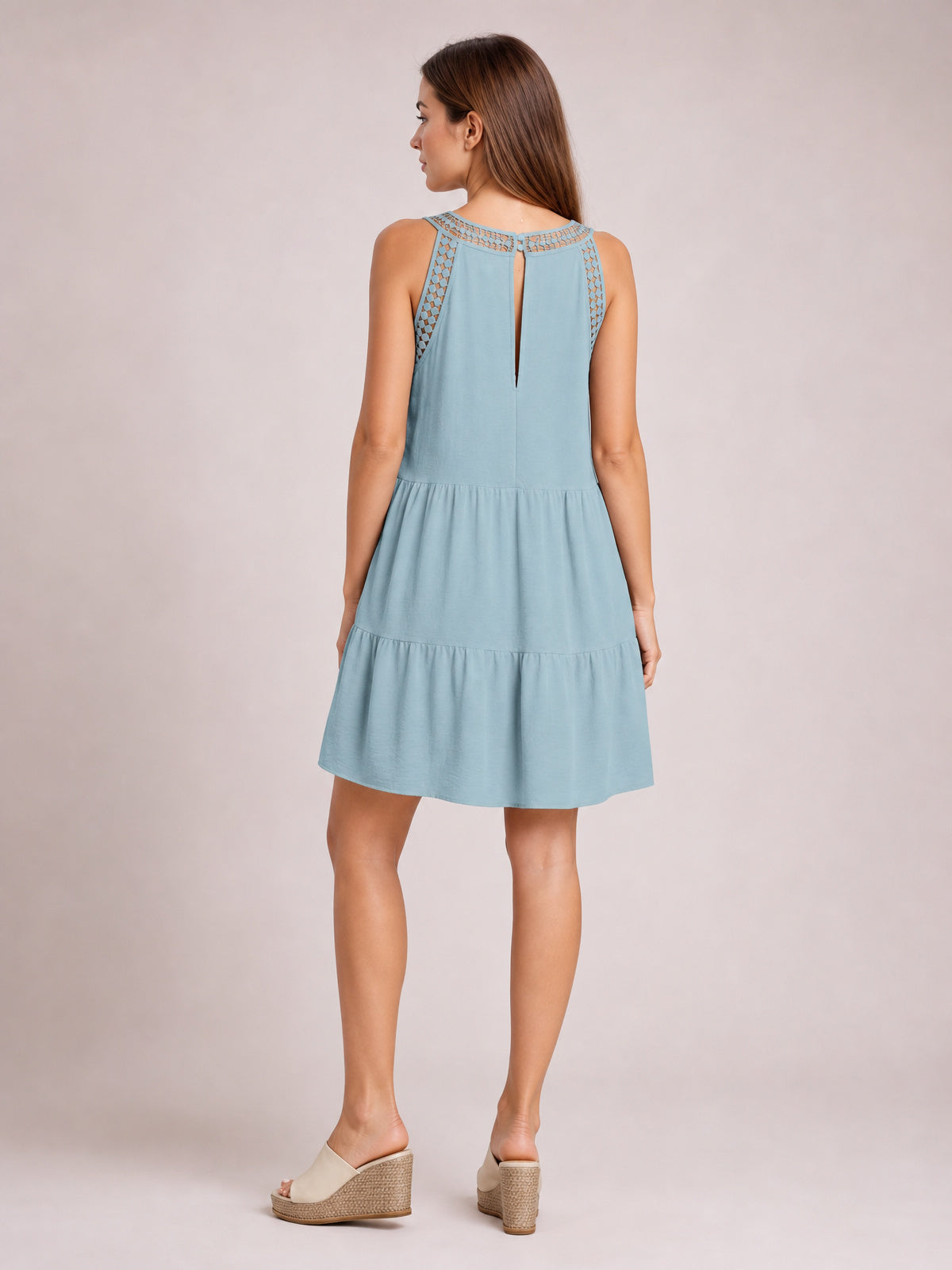 Model shown from the back in a light blue sleeveless lace dress with lace-trimmed shoulders, a relaxed tiered silhouette, and a softly flared hem.