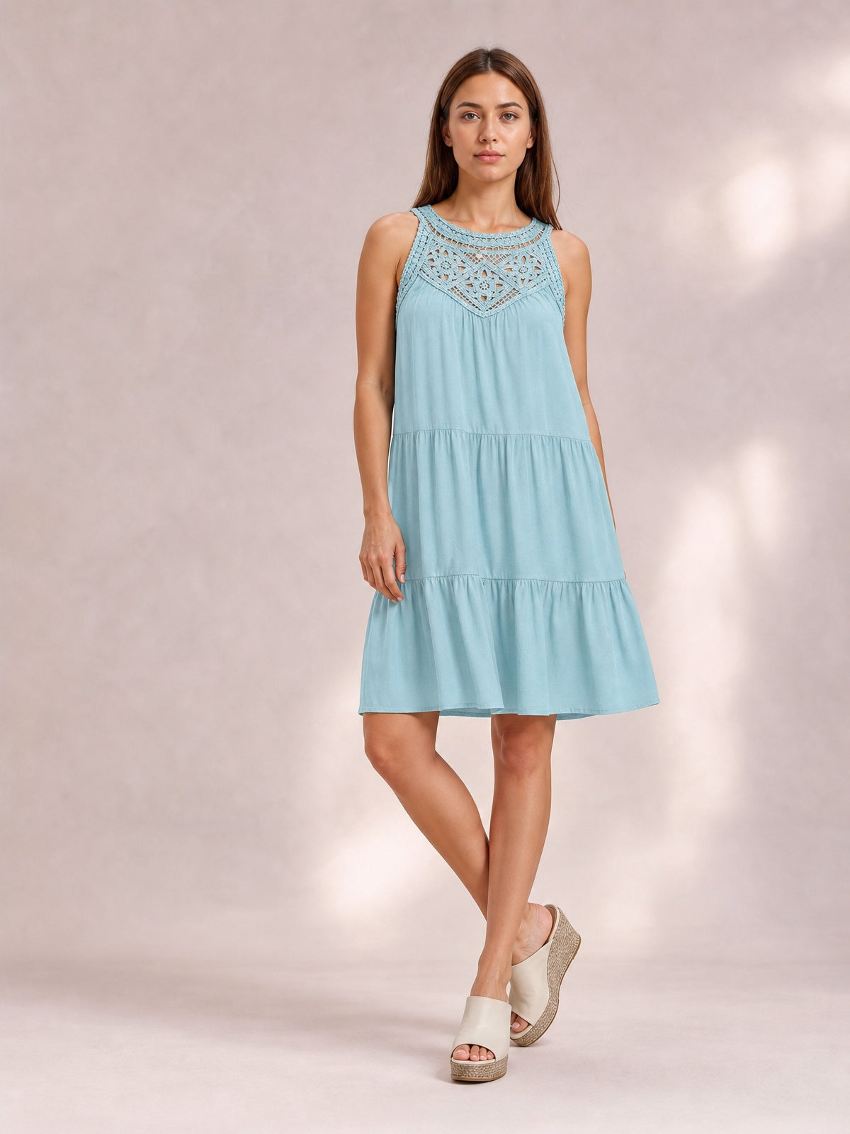 A model poses in a light blue ruffled hem lace sleeveless dress with a relaxed tiered silhouette, gathered skirt, and intricate lace bodice.