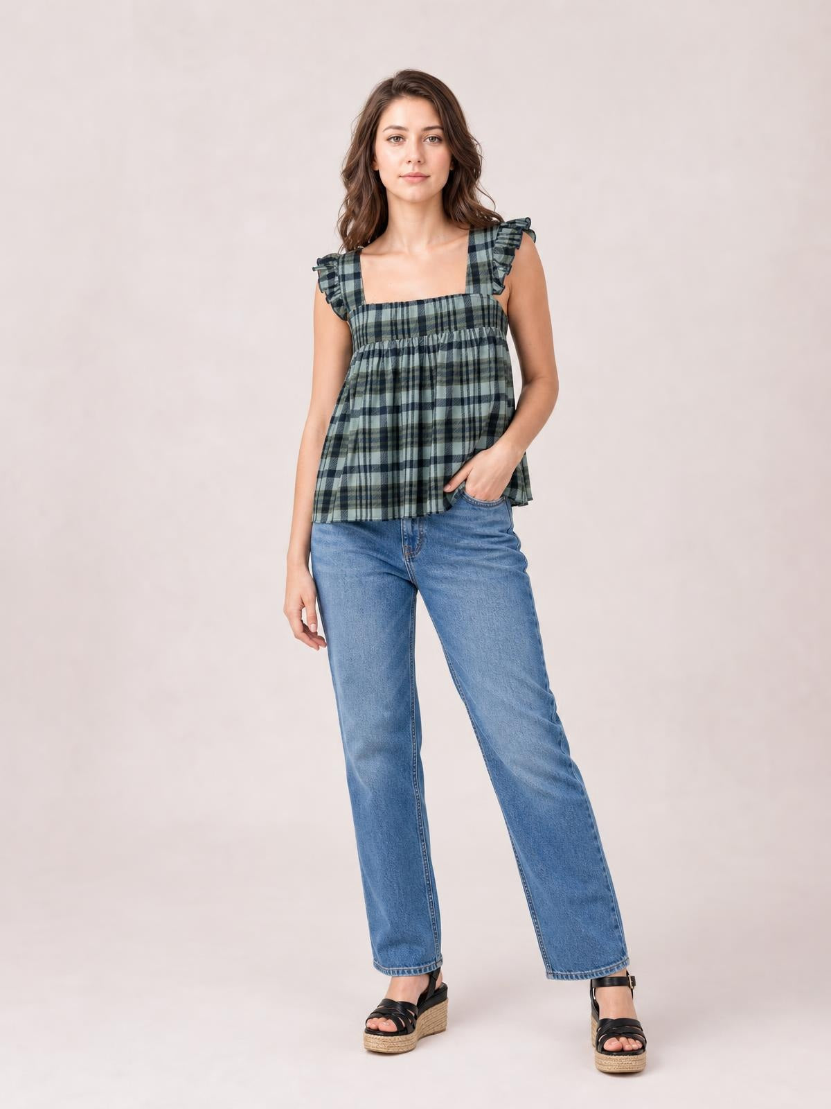 Model poses in a green and navy plaid tank with a square neckline, ruffled shoulder straps, and a gathered, relaxed silhouette.