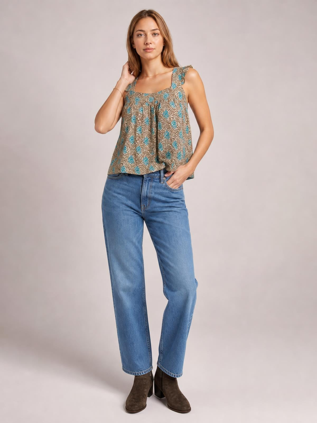 A model poses in a taupe patterned tank with a square neckline, wide ruffled straps, and a loose, flowy silhouette.