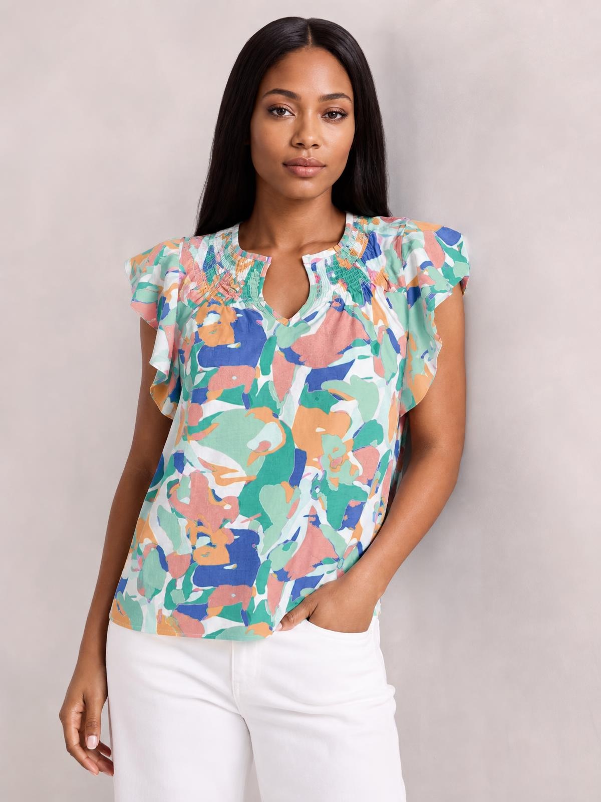 Model poses in a colorful printed blouse with ruffled cap sleeves, a notched neckline, and a relaxed straight silhouette.