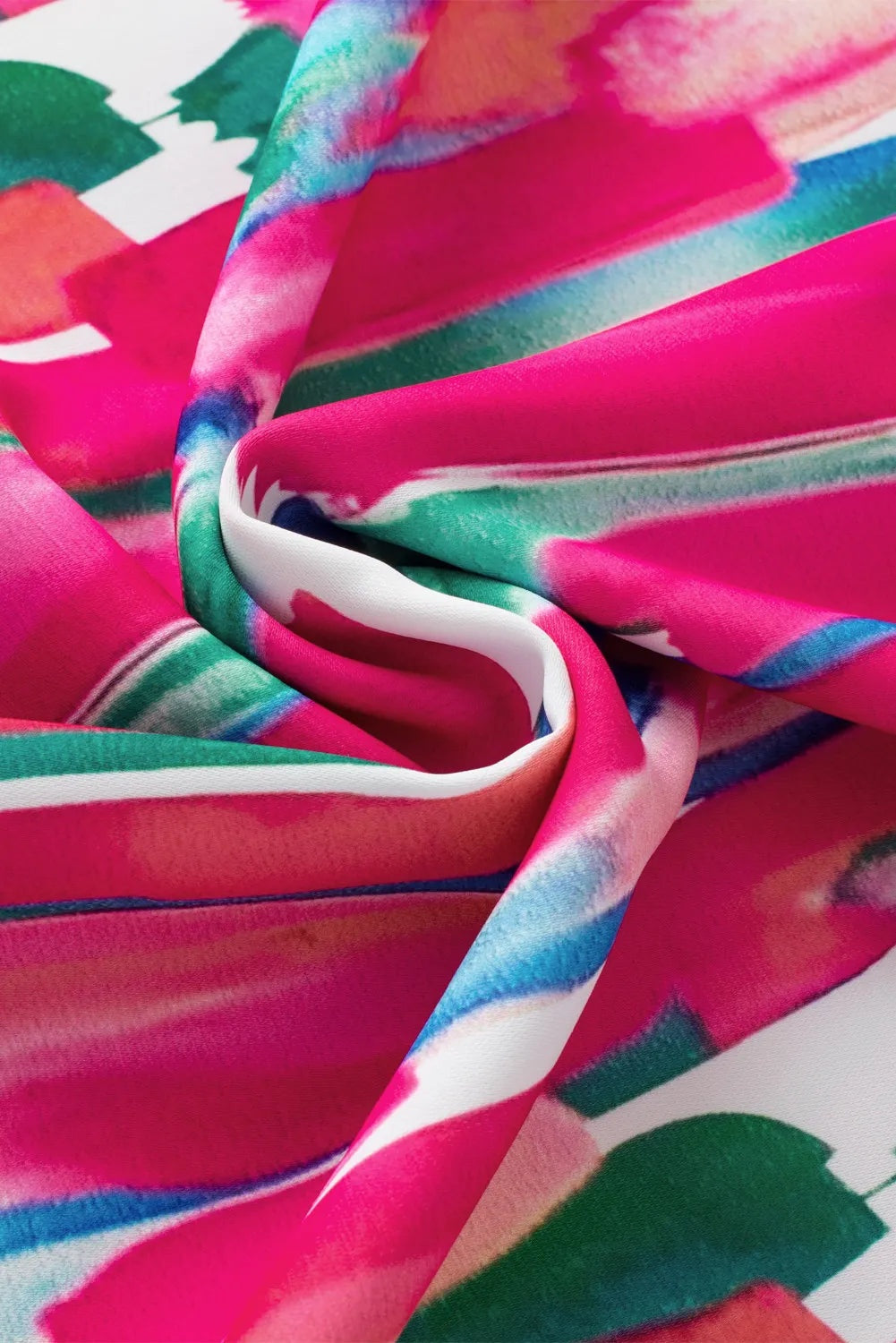 Close-up of the blouse’s vivid pink printed fabric, featuring abstract teal, blue, white, and coral accents in softly draped folds.