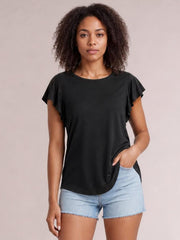 Model wearing a black ruffled round neck cap sleeve blouse with a relaxed straight silhouette, standing with one hand in her shorts pocket.