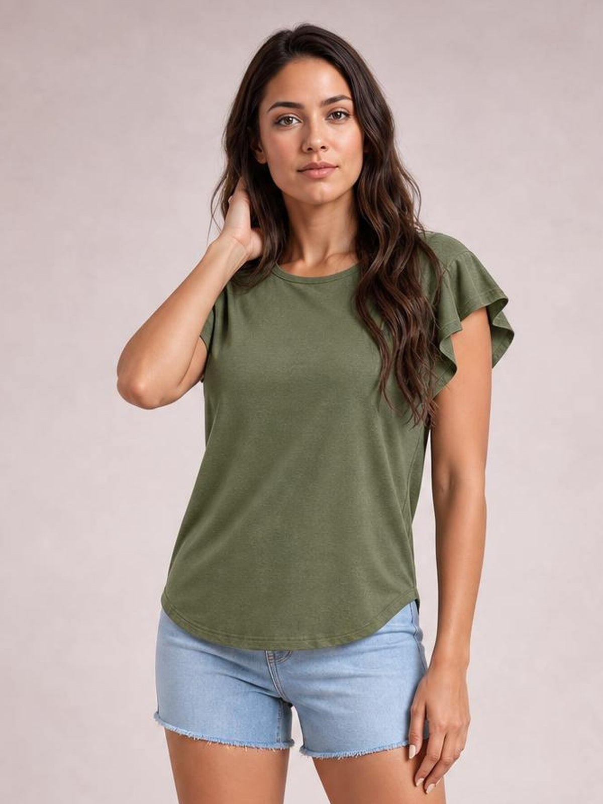 A woman models an olive green ruffled round-neck blouse with layered cap sleeves and a relaxed straight silhouette while touching her hair.