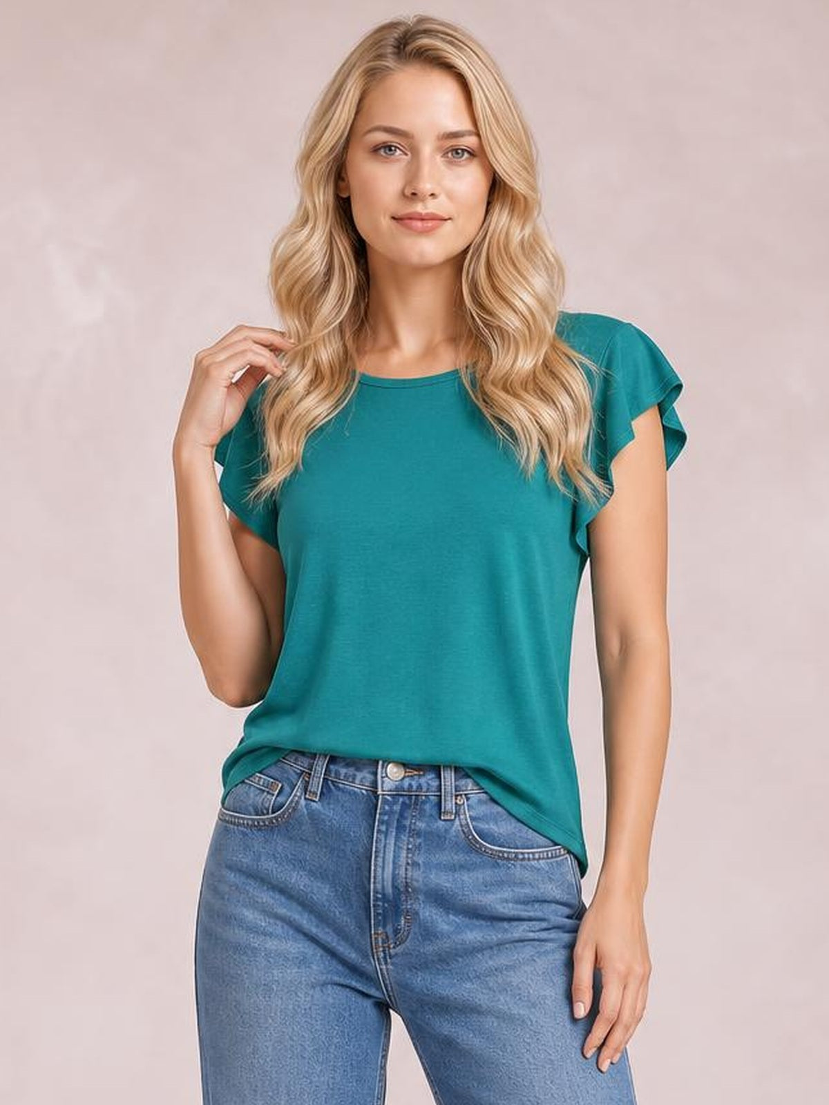 A model poses in a teal ruffled round-neck cap-sleeve blouse with a relaxed straight silhouette, gently touching her hair.