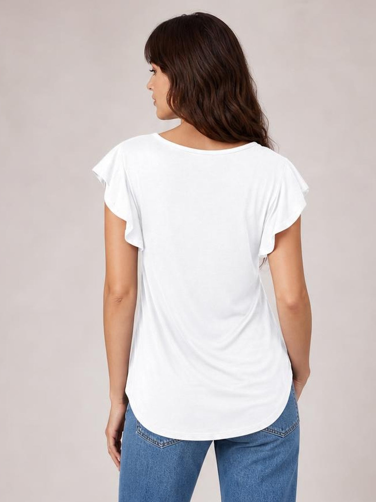 Model shown from behind wearing a white ruffled round-neck blouse with cap sleeves, a relaxed silhouette, and a curved shirttail hem.