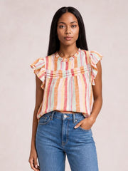 Model wearing a multicolor striped round neck blouse with layered ruffles, fluttering cap sleeves, and a loose straight silhouette, one hand in her jeans pocket.