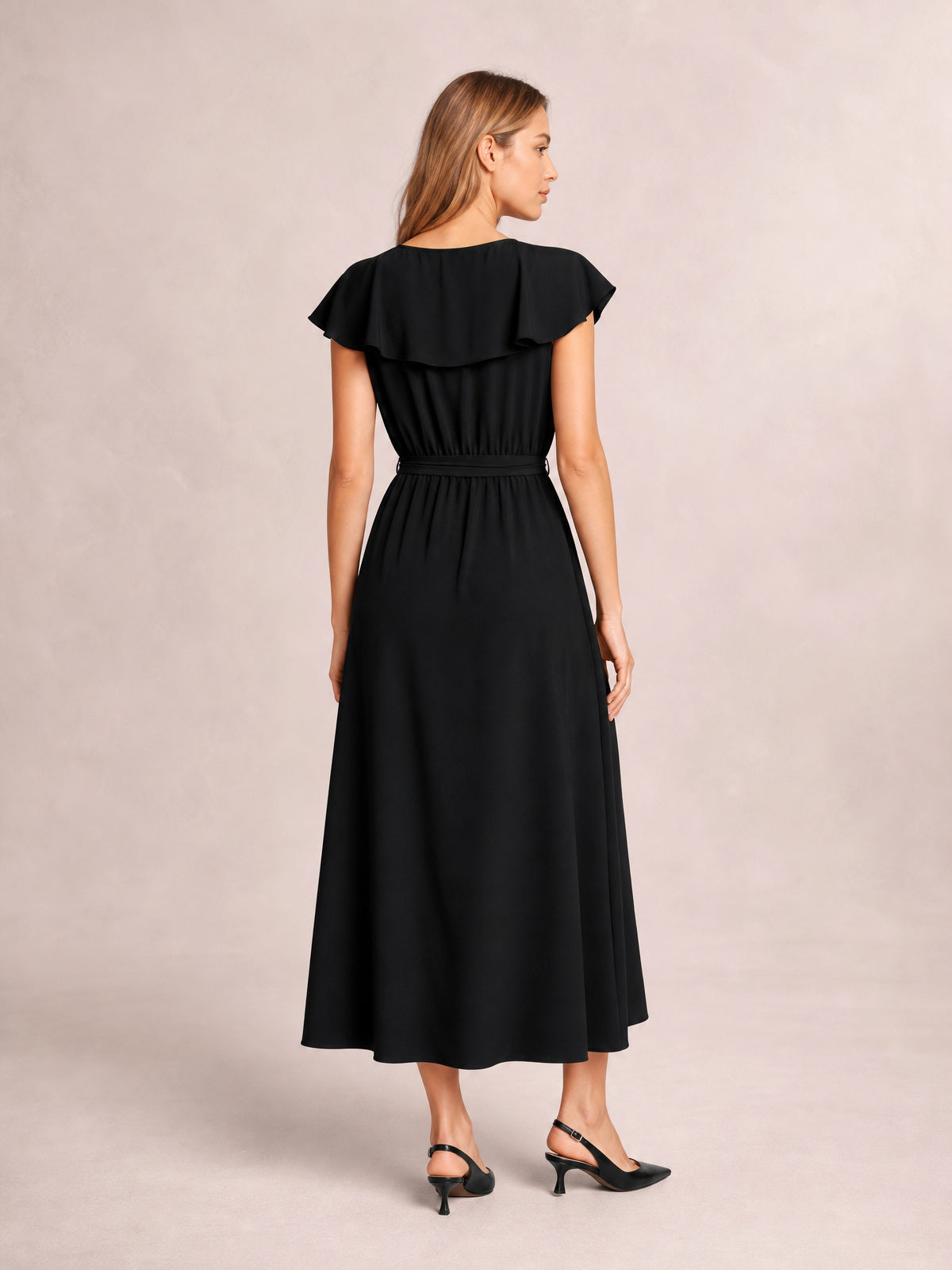 A model poses in a black ruffled midi dress, showing flutter sleeves, a defined waist, flowing A-line silhouette, and a subtle side slit.
