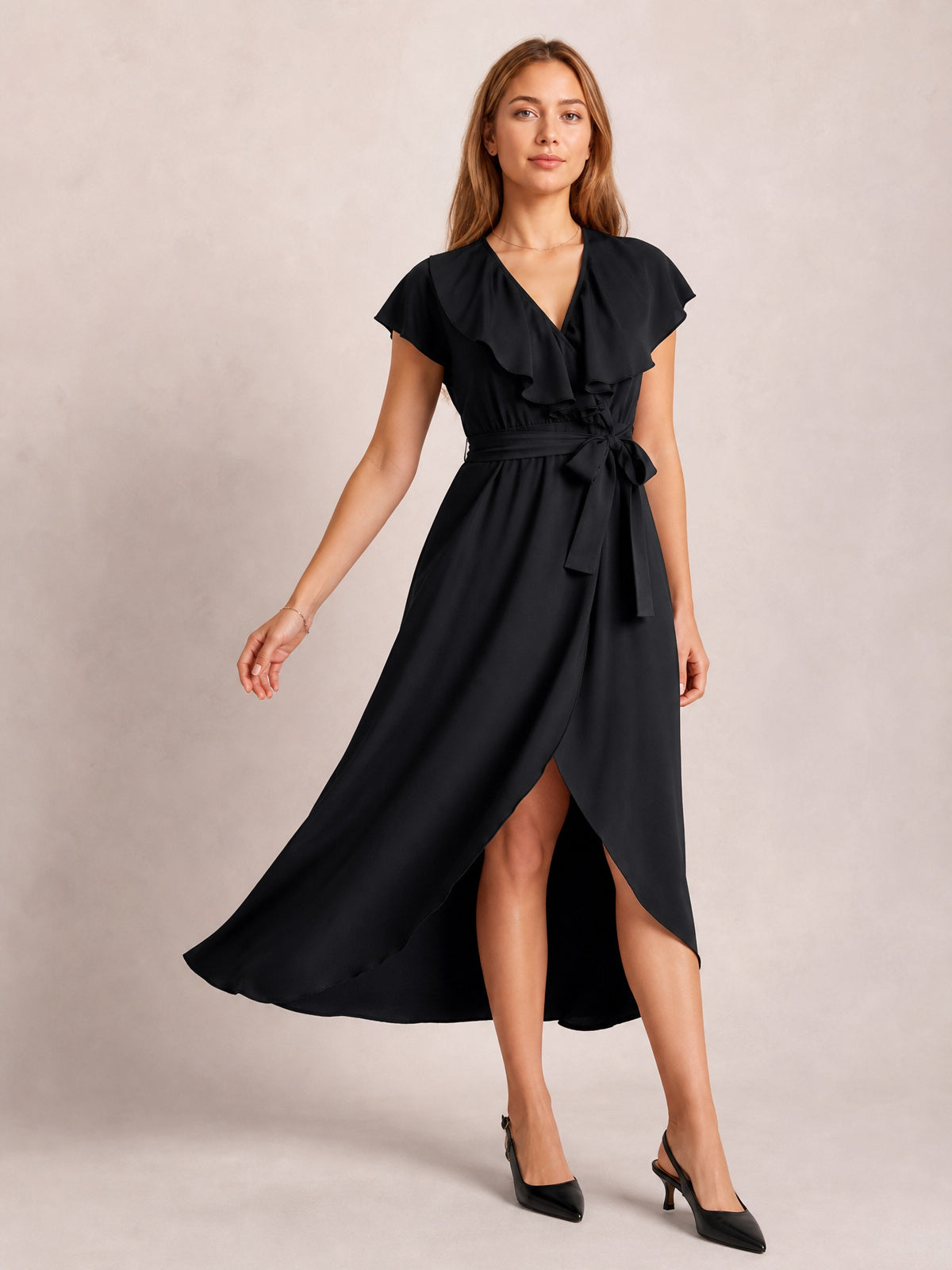 Model poses in a black ruffled surplice midi dress with flutter sleeves, a tied waist, flowing silhouette, and leg-baring slit.