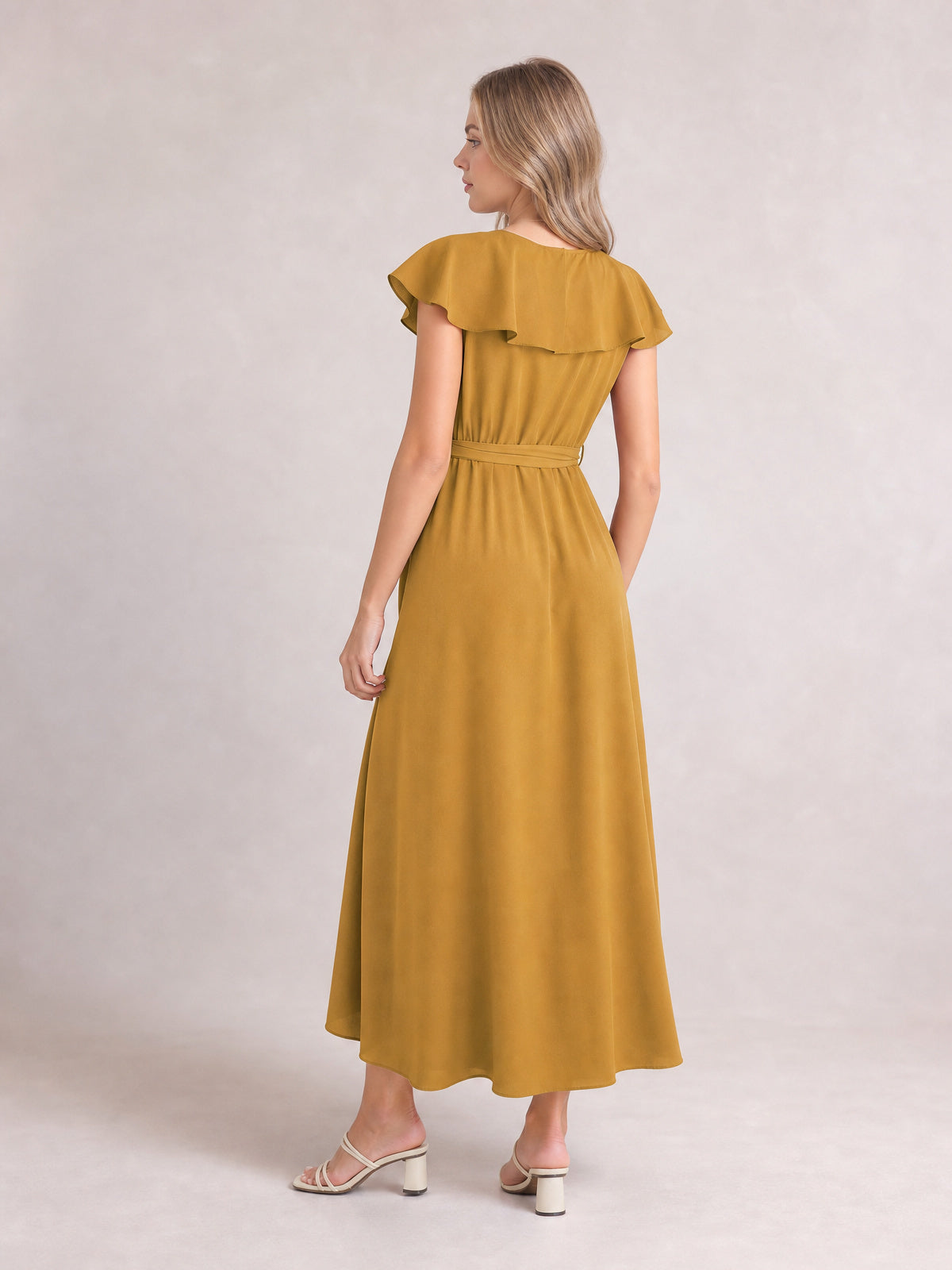 Model in a mustard ruffled midi dress shows its flowing A-line silhouette, flutter sleeves, and defined tie waist from the back.