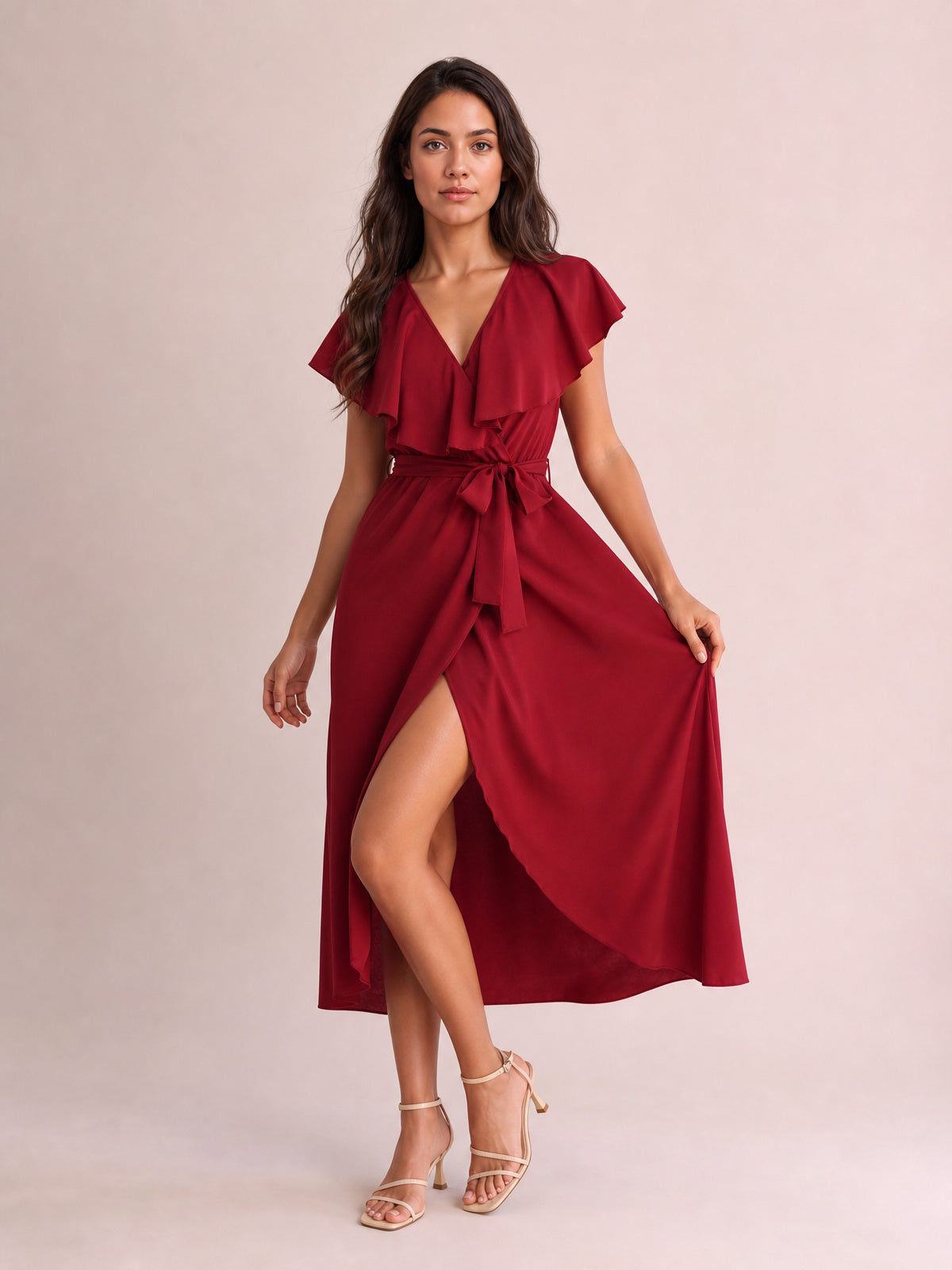 Model in a burgundy ruffled surplice midi dress with flutter sleeves, a tied waist, flowing silhouette, and leg-baring front slit.