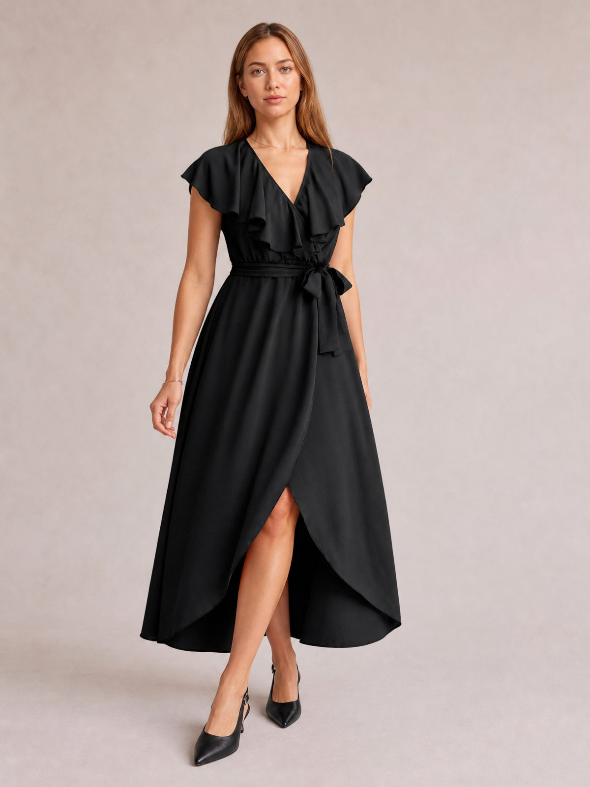 Model in a black ruffled surplice midi dress with flutter sleeves, a tied waist, flowing silhouette, and leg-baring front slit.