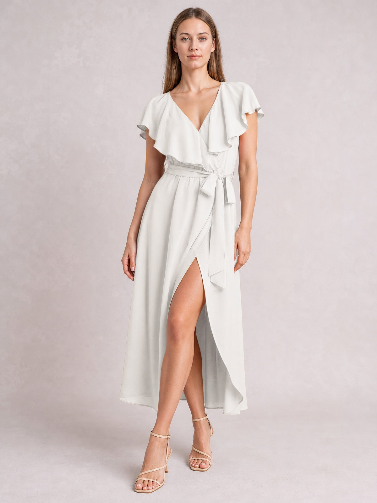 A model stands in a white ruffled surplice midi dress with flutter sleeves, a tied waist, flowing silhouette, and front leg-baring slit.