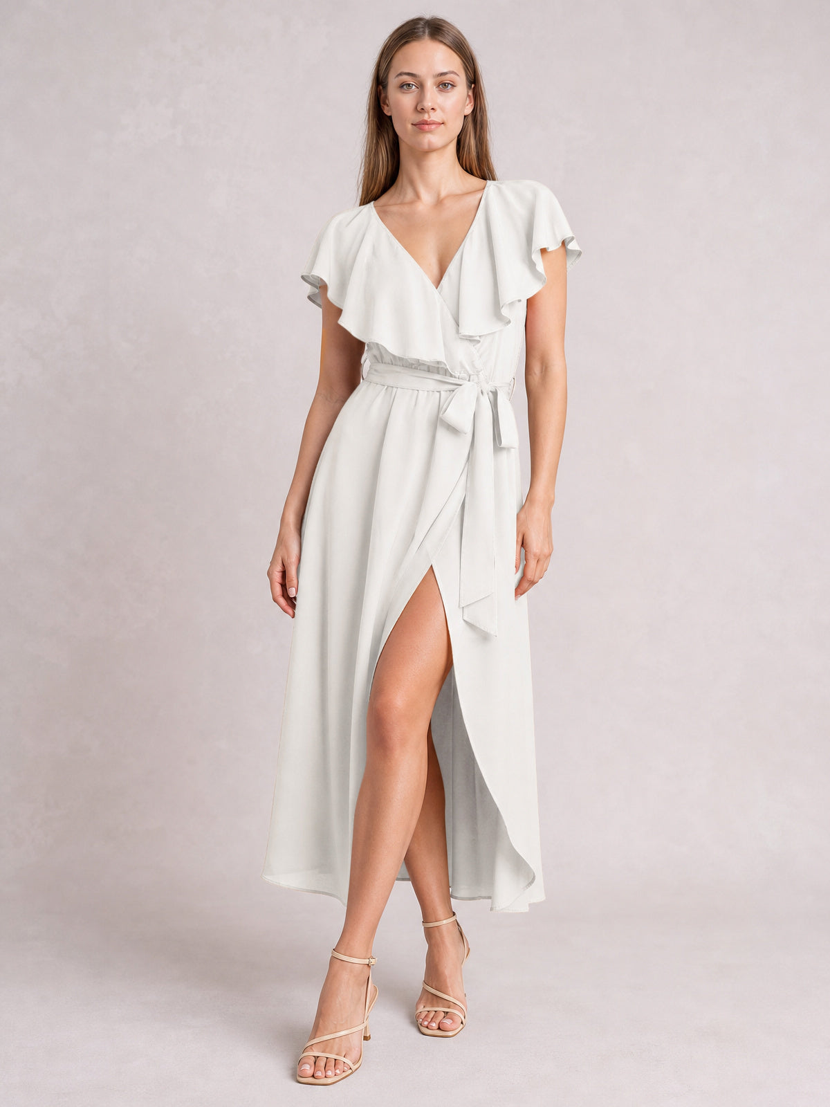 A model stands in a white ruffled surplice midi dress with flutter sleeves, a tied waist, flowing silhouette, and front leg-baring slit.