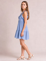 Model poses in a light blue ruffled tiered cami mini dress with frill-trimmed straps, a softly gathered neckline, and a flared skirt.