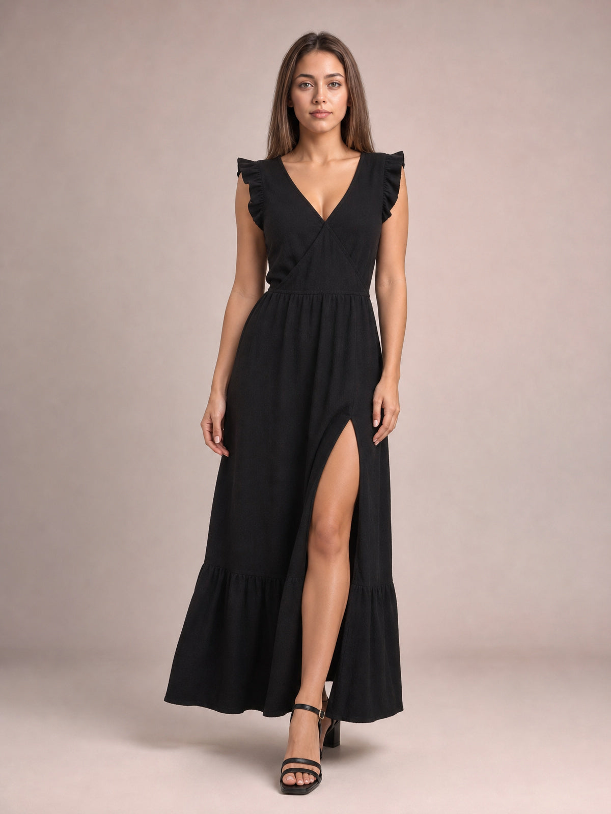 Model wears a black ruffled V-neck cap sleeve maxi dress with a gathered waist, flowing tiered skirt, and visible side slit.