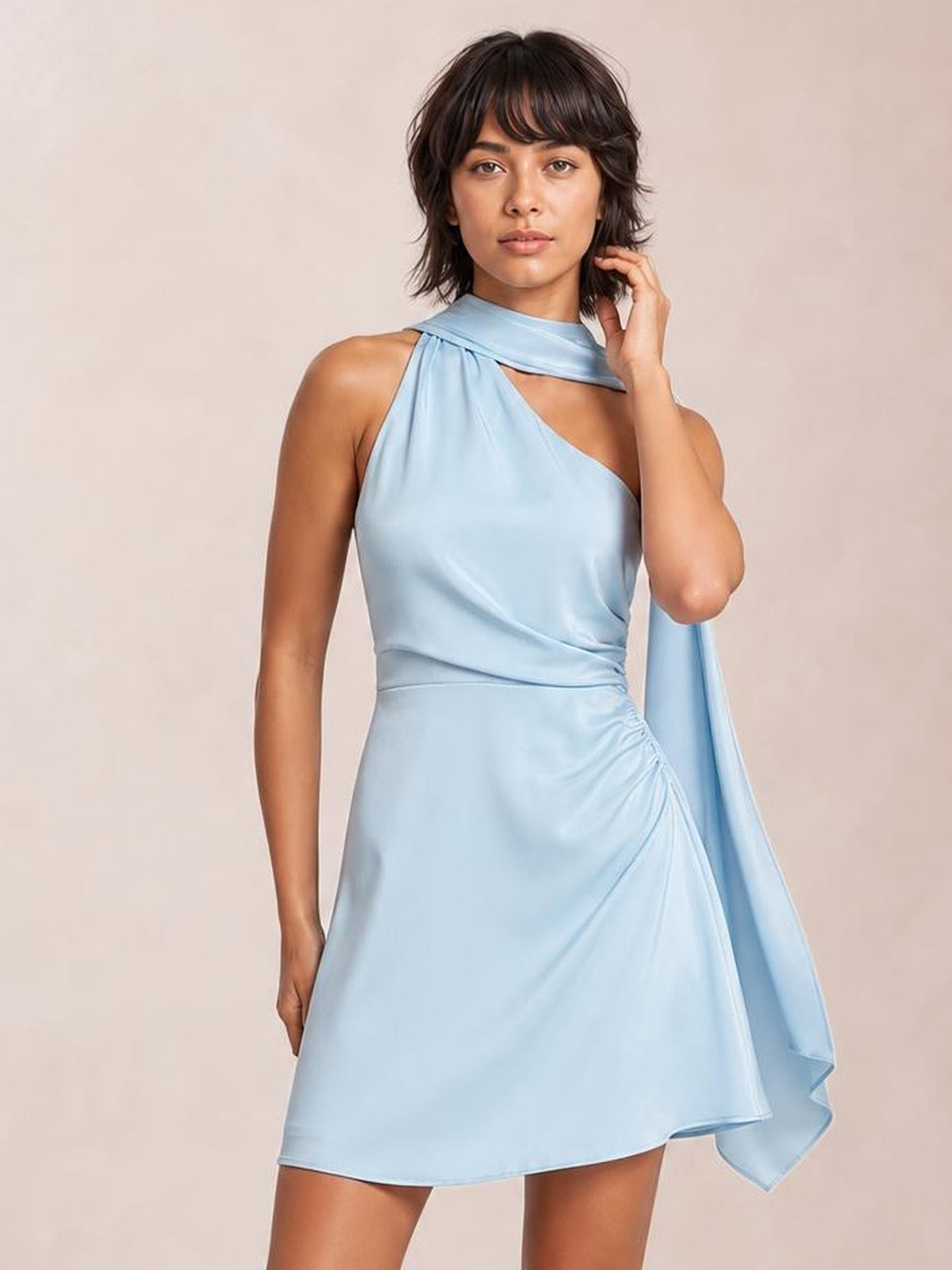 Model wearing a light blue satin one-shoulder mini dress with a draped neckline, ruched hip detail, fitted waist, and flowing side sash.