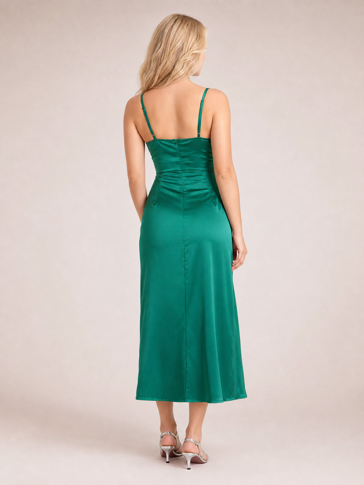 Model shown from behind in a green satin spaghetti strap midi dress with a fitted bodice, defined waist, center-back seam, and softly flared silhouette.