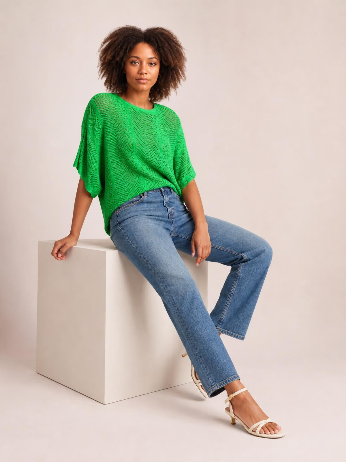 A model sits in a bright green scallop-edge half-sleeve pointelle knit top with openwork texture and a relaxed, draped silhouette.