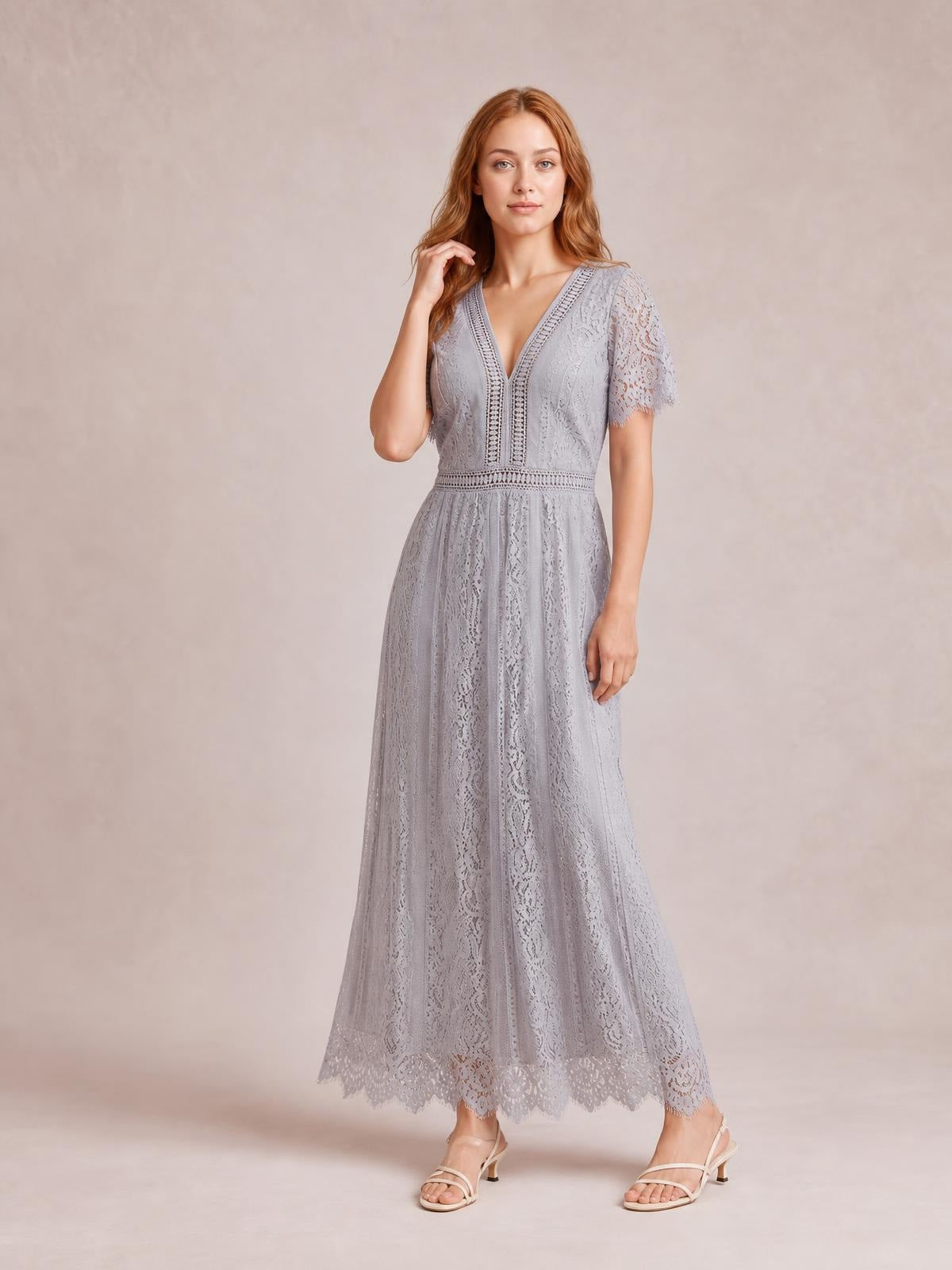Model standing in a light gray lace plunge maxi dress with short sleeves, a fitted waist, flowing silhouette, and scalloped lace trim at the hem.