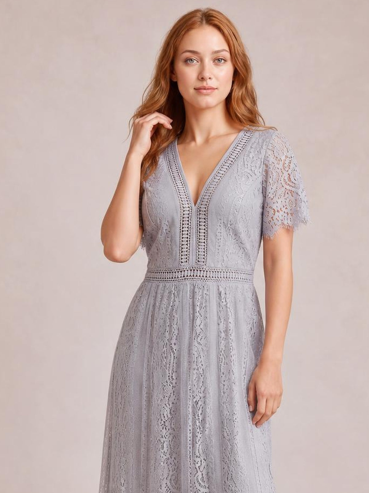 A model poses in a light gray lace maxi dress with a plunging V-neck, scalloped sleeve trim, short sleeves, a defined waist, and a flowing silhouette.
