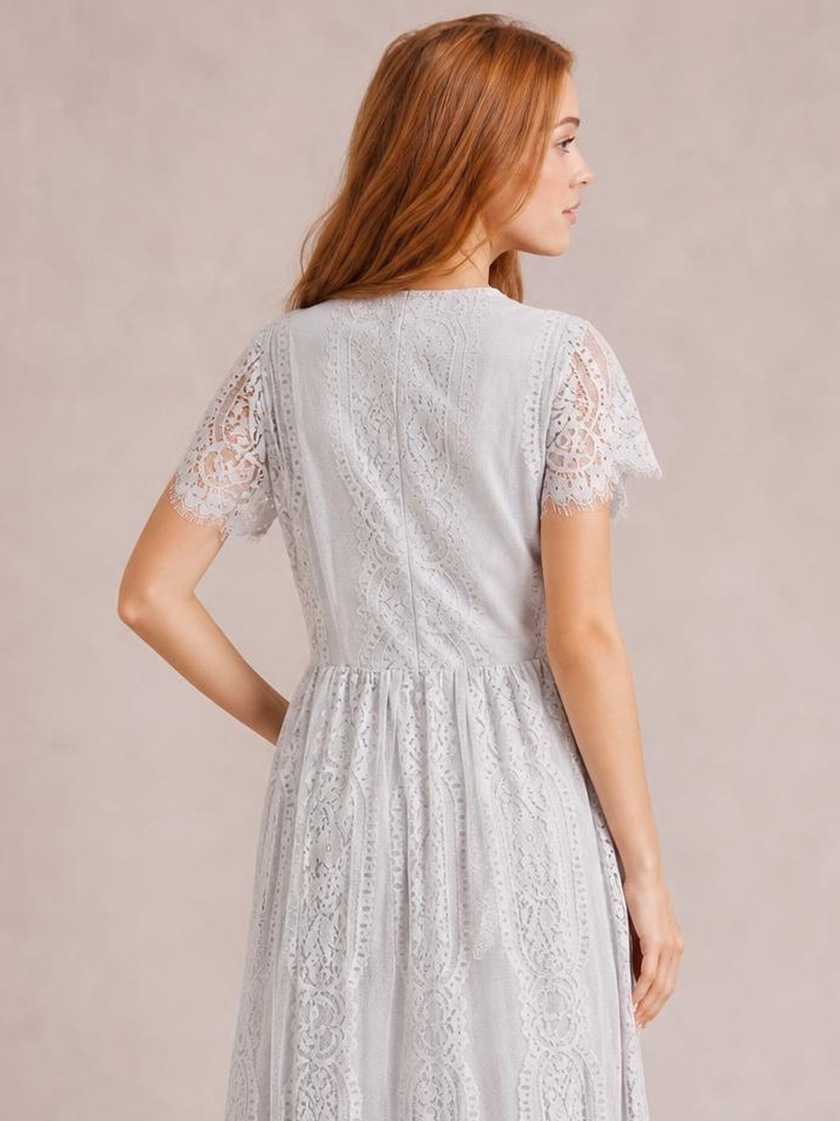 A model poses in a white lace maxi dress with short scalloped-trim sleeves, a fitted waist, textured back, and flowing full skirt.