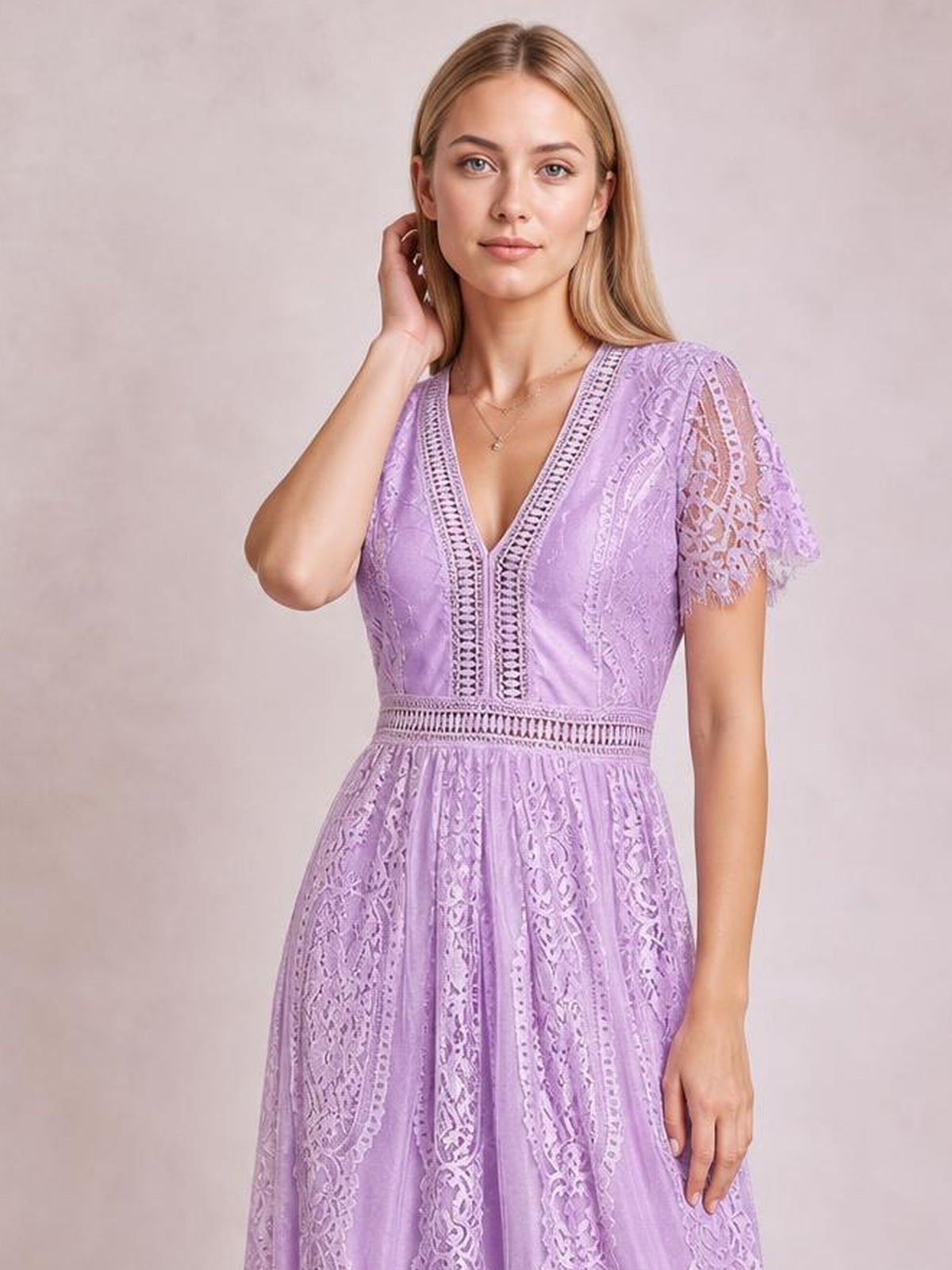 A model poses in a lavender lace plunge maxi dress with a deep V-neck, short scalloped sleeves, defined waist, and flowing A-line silhouette.