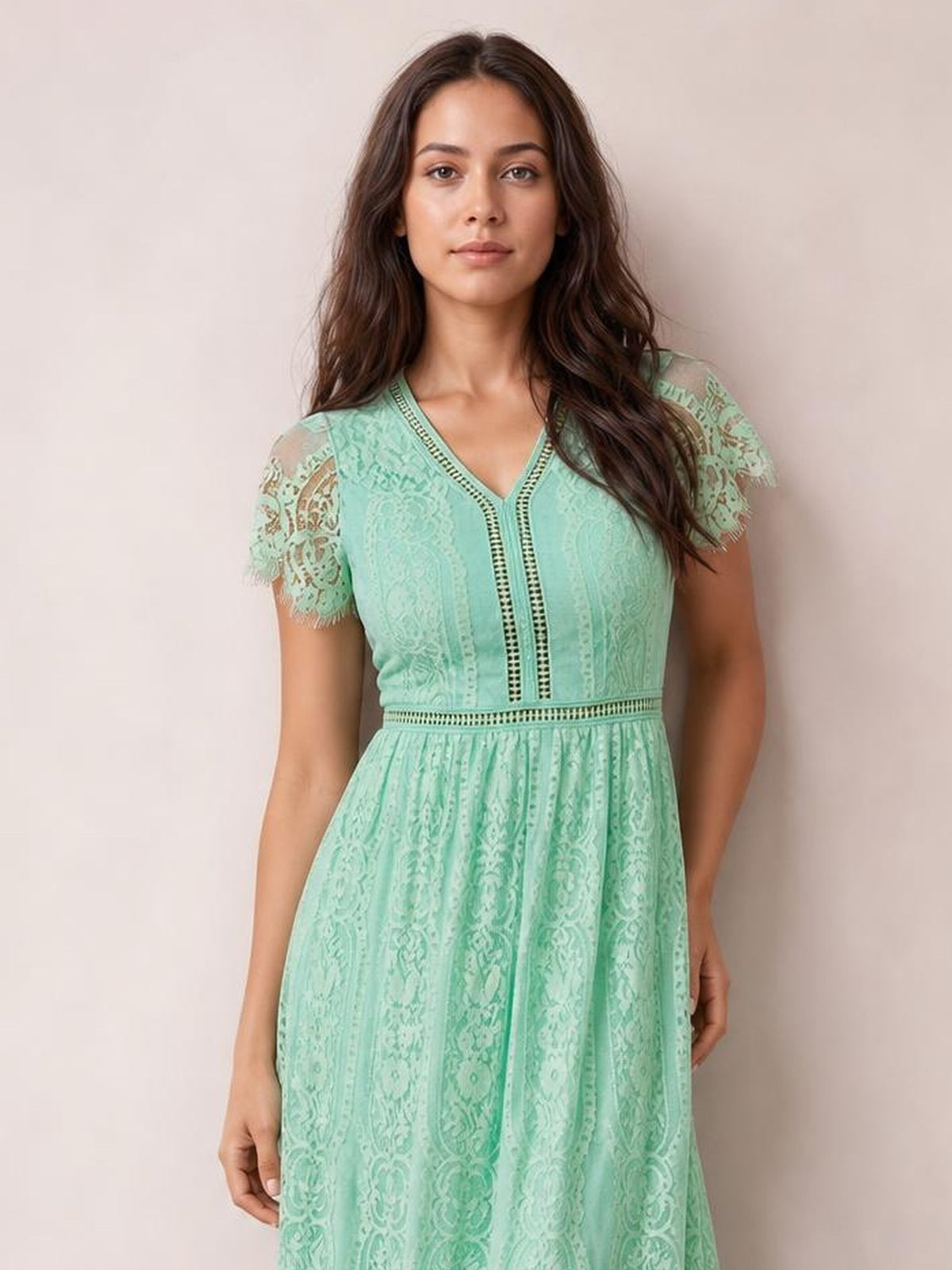 A model stands in a mint-green lace plunge maxi dress with a V-neck, short scalloped sleeves, fitted bodice, defined waist, and flowing flared skirt.